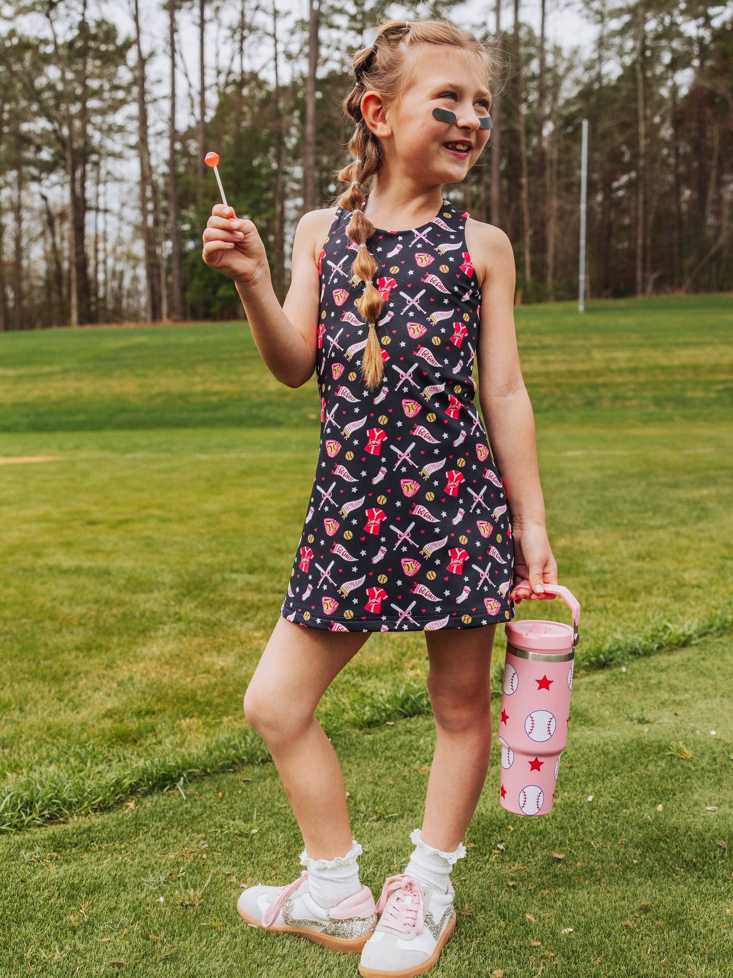 Girl outside holding a sucker and a pink softball printed water bottle