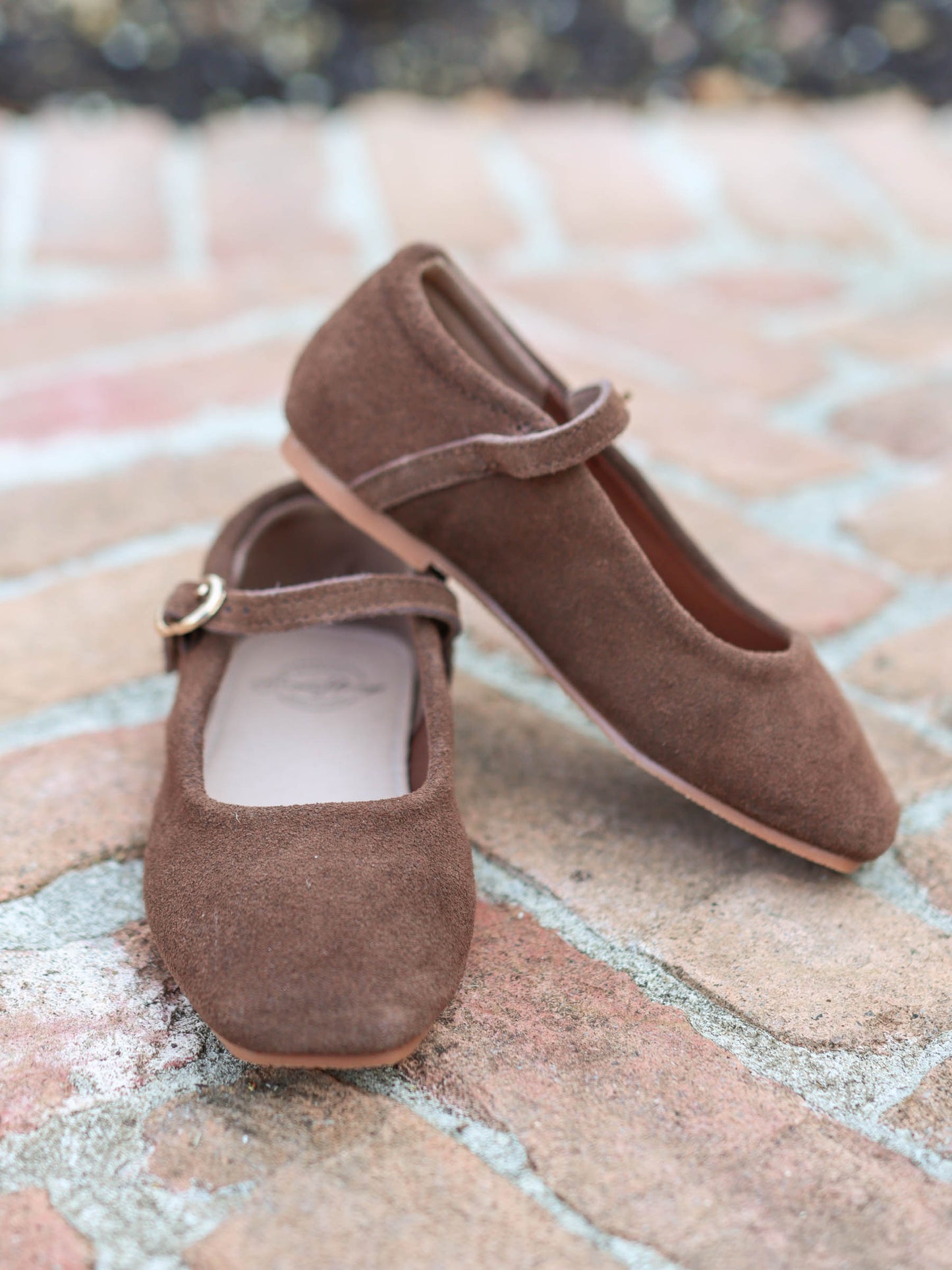 A rich brown square toe ballet style Mary Jane with functional metal clasp and rubber soles. 