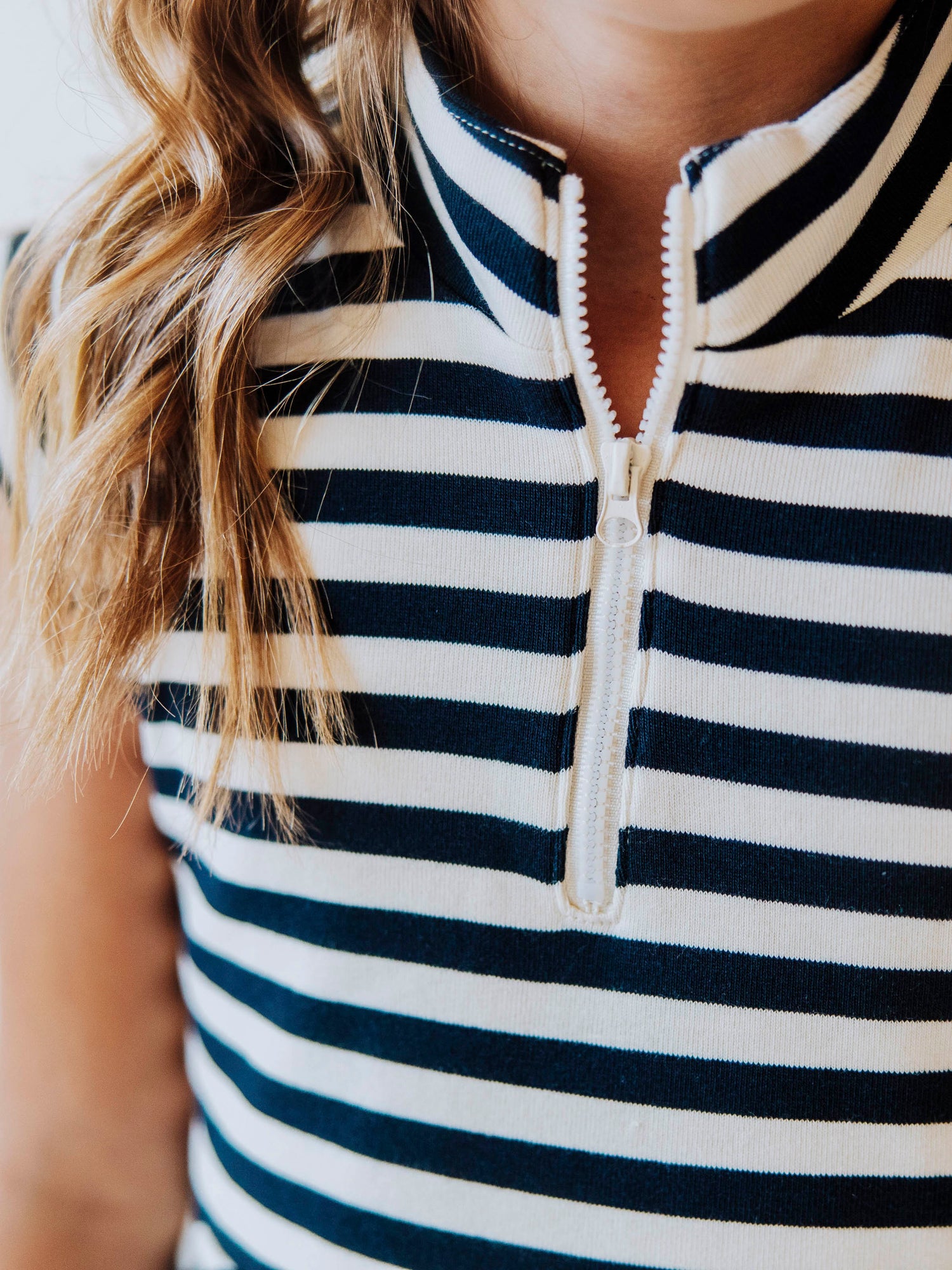 Up close picture of the zipper closure on navy and cream colored dress. 