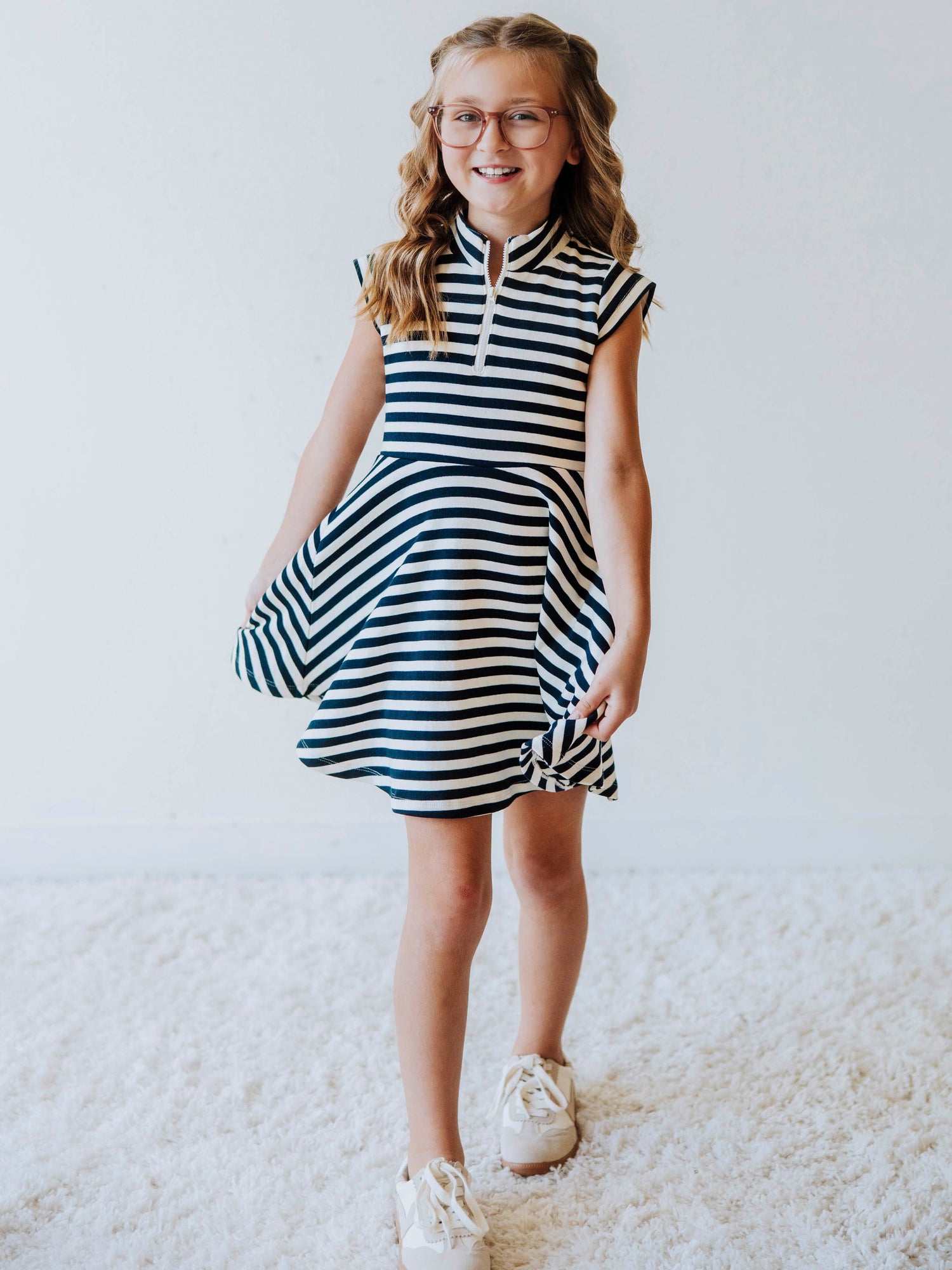 Model is wearing a navy and ivory striped dress with cream colored shoes. 