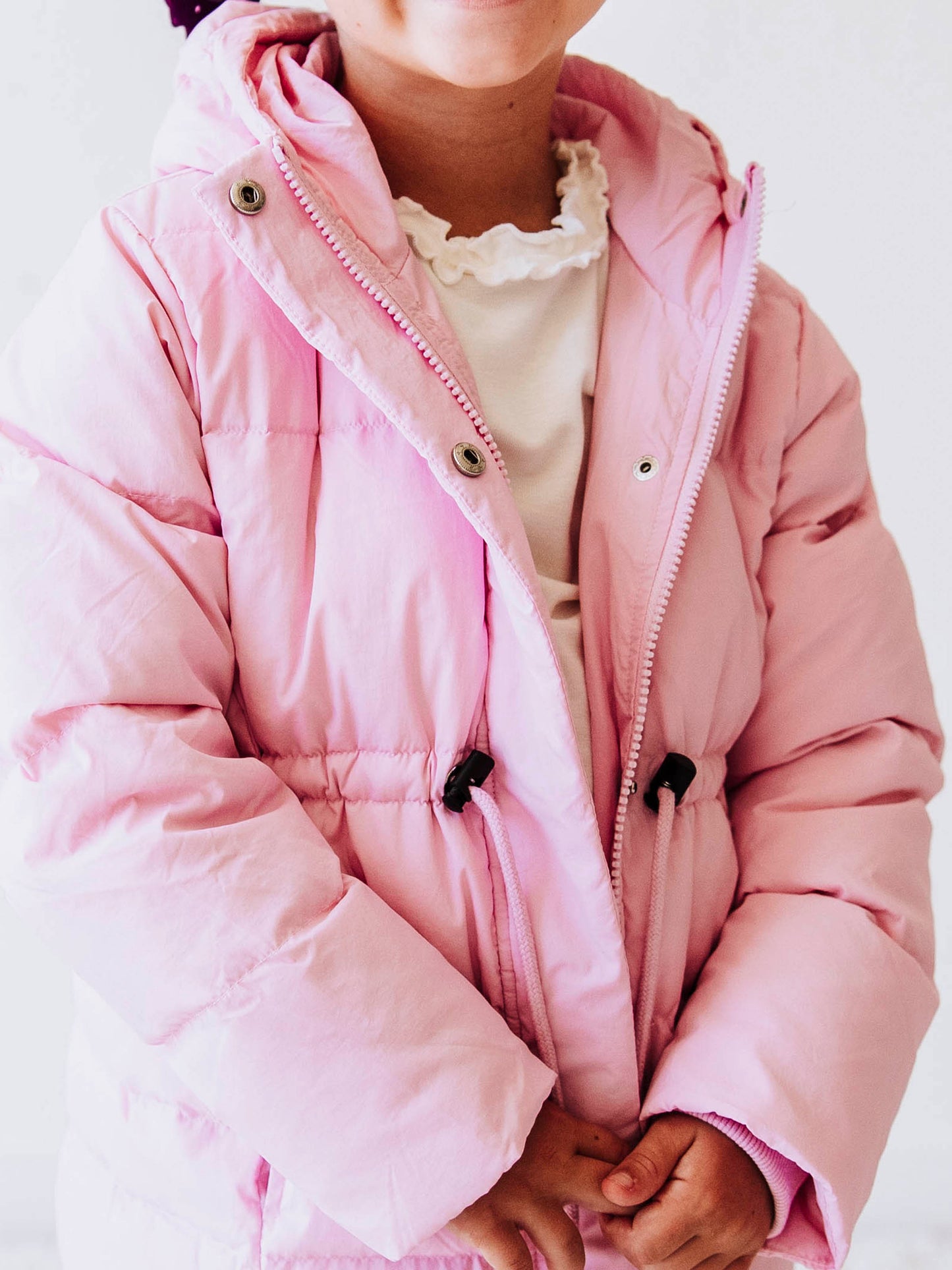Keep her cozy and cute all season long in our Pink Puffer Jacket — the perfect blend of warmth and style! This soft, quilted jacket features a full zipper closure with a button placket, ensuring extra protection from chilly winds. Hidden front pockets keep little hands warm (or treasures tucked away), while the adjustable waist toggle allows for the perfect, comfortable fit. Designed in a beautiful blush pink hue, this girls’ puffer jacket pairs effortlessly with any winter outfit for a look that's fun!