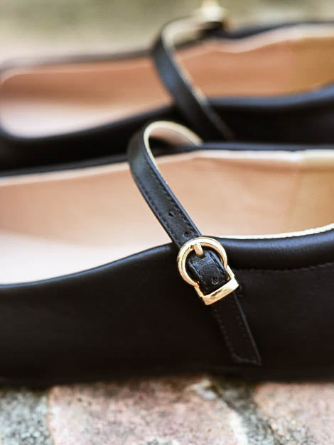 Up close picture of a clasp buckle closure on a pair of black ballet mary janes