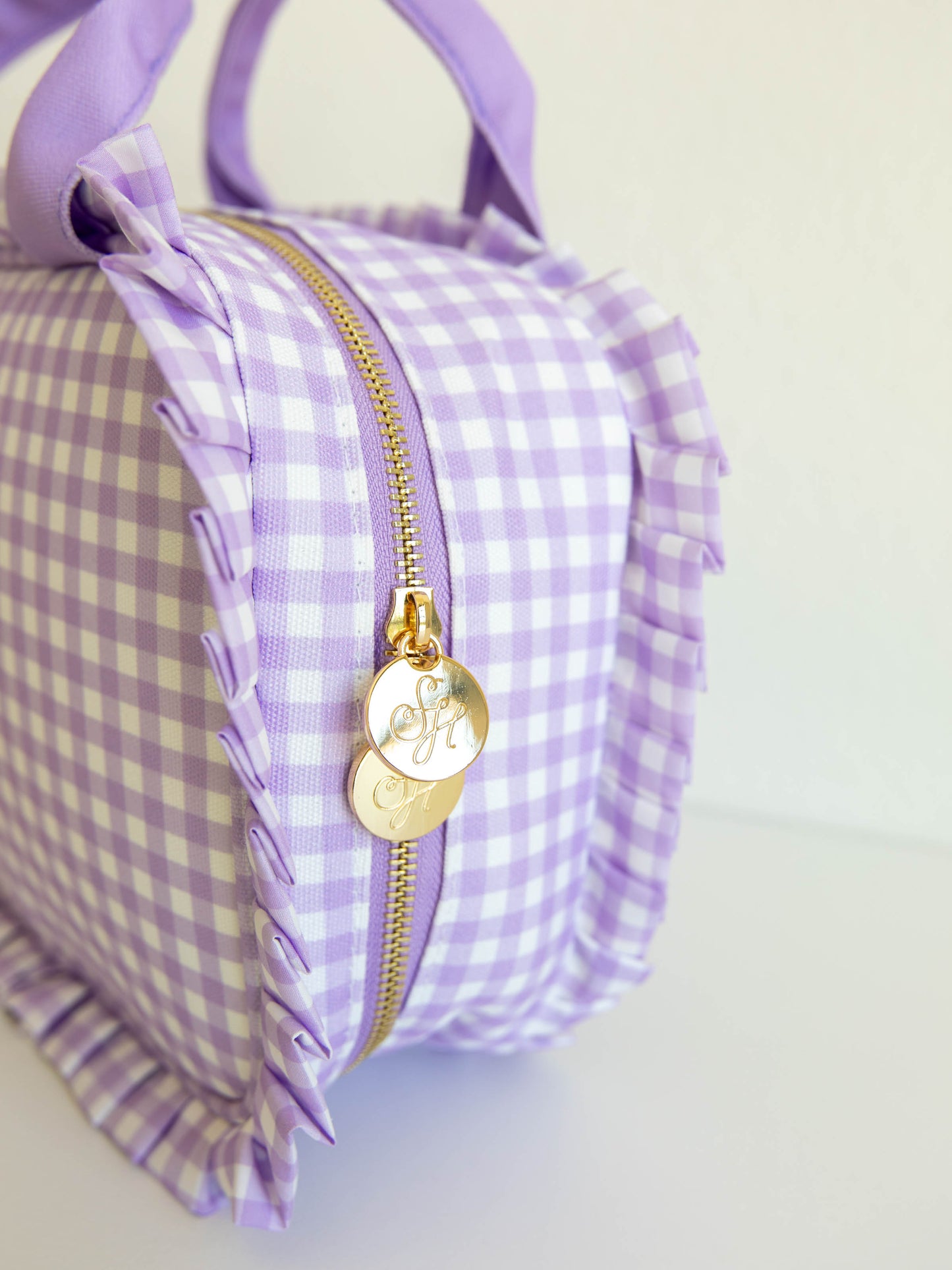 Detail shot of purple check lunch kit with purple handles and ruffled edge details showing gold zipper pulls.