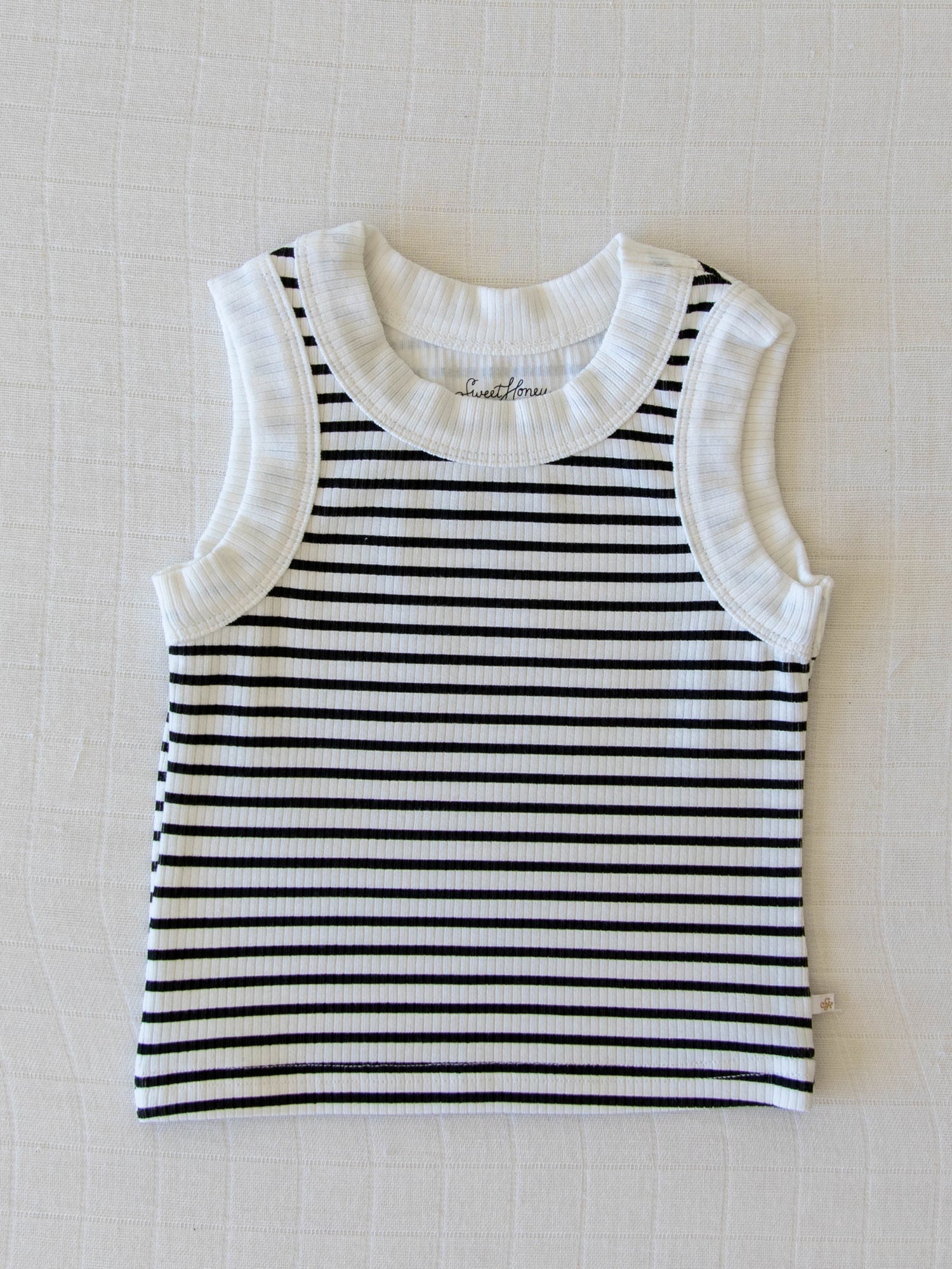 Flay lay of a ribbed black and white stripe tank top with white neck and arm holes. 