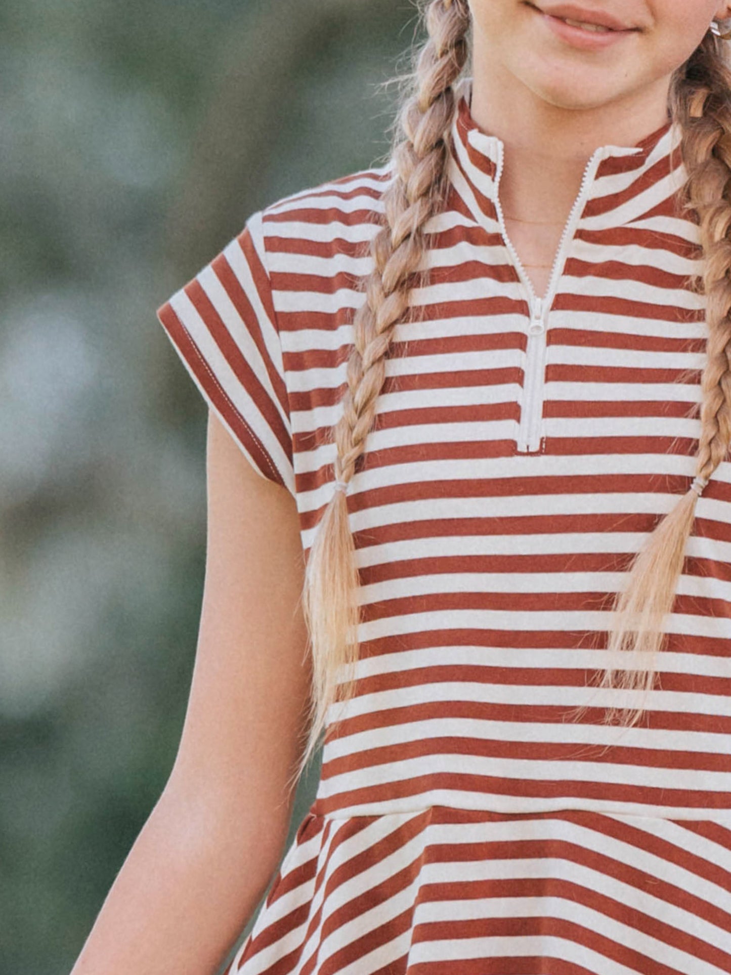 Up close picture of a model wearing a chocolate and ivory striped dress that has cap sleeves and a zipper at chest. 