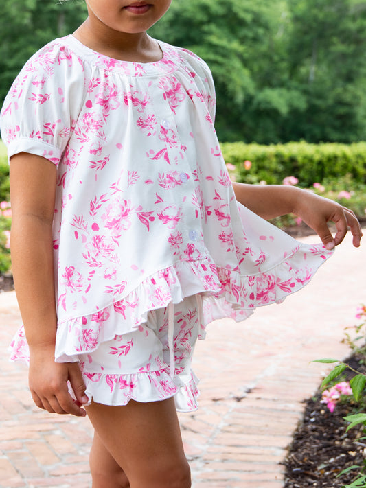 Girl is outside wearing a white with pink floral print two-piece set.