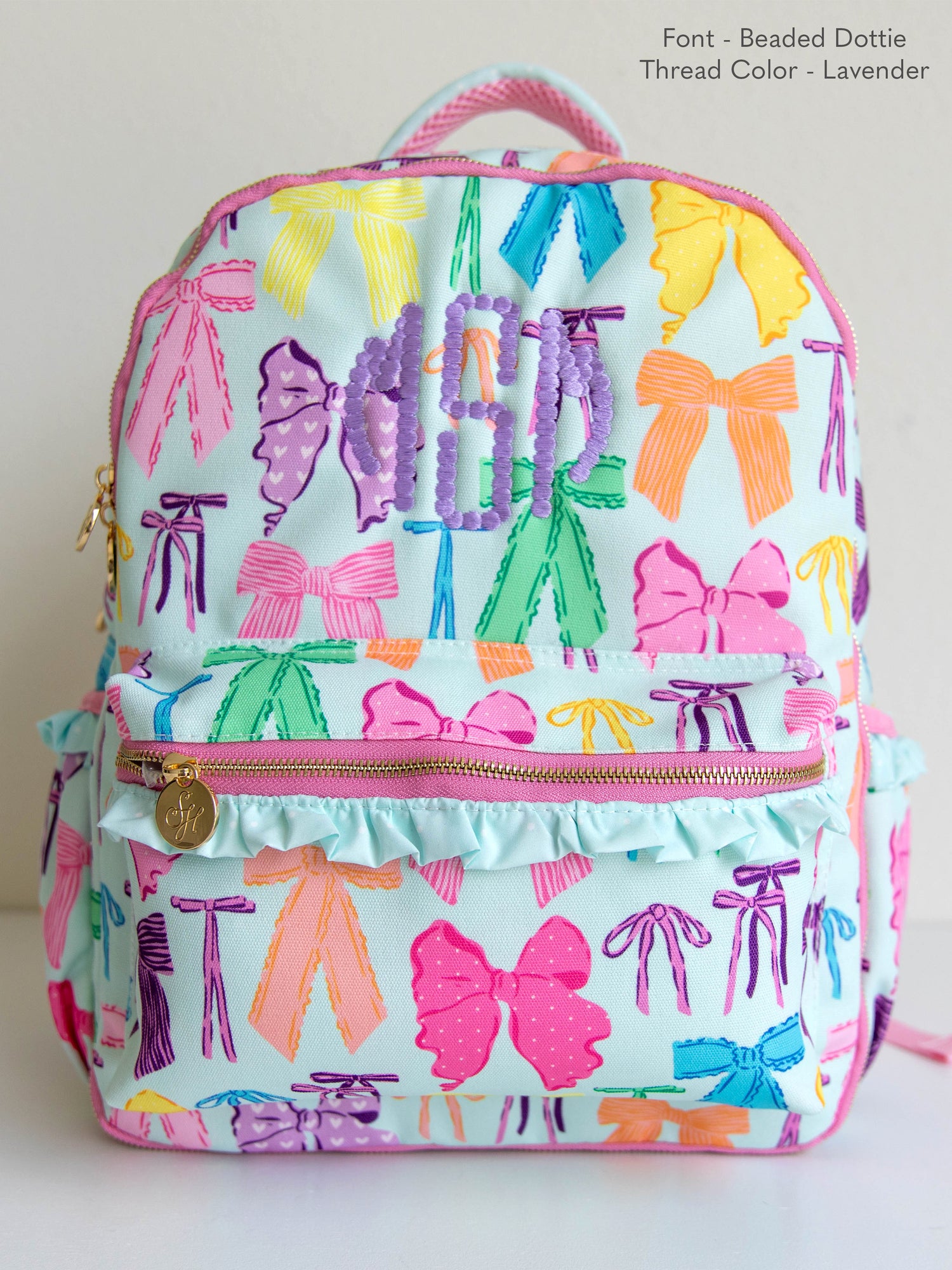 Vibrant bows printed backpack with customized embroidery, gold zippers and zipper pulls, and a handle