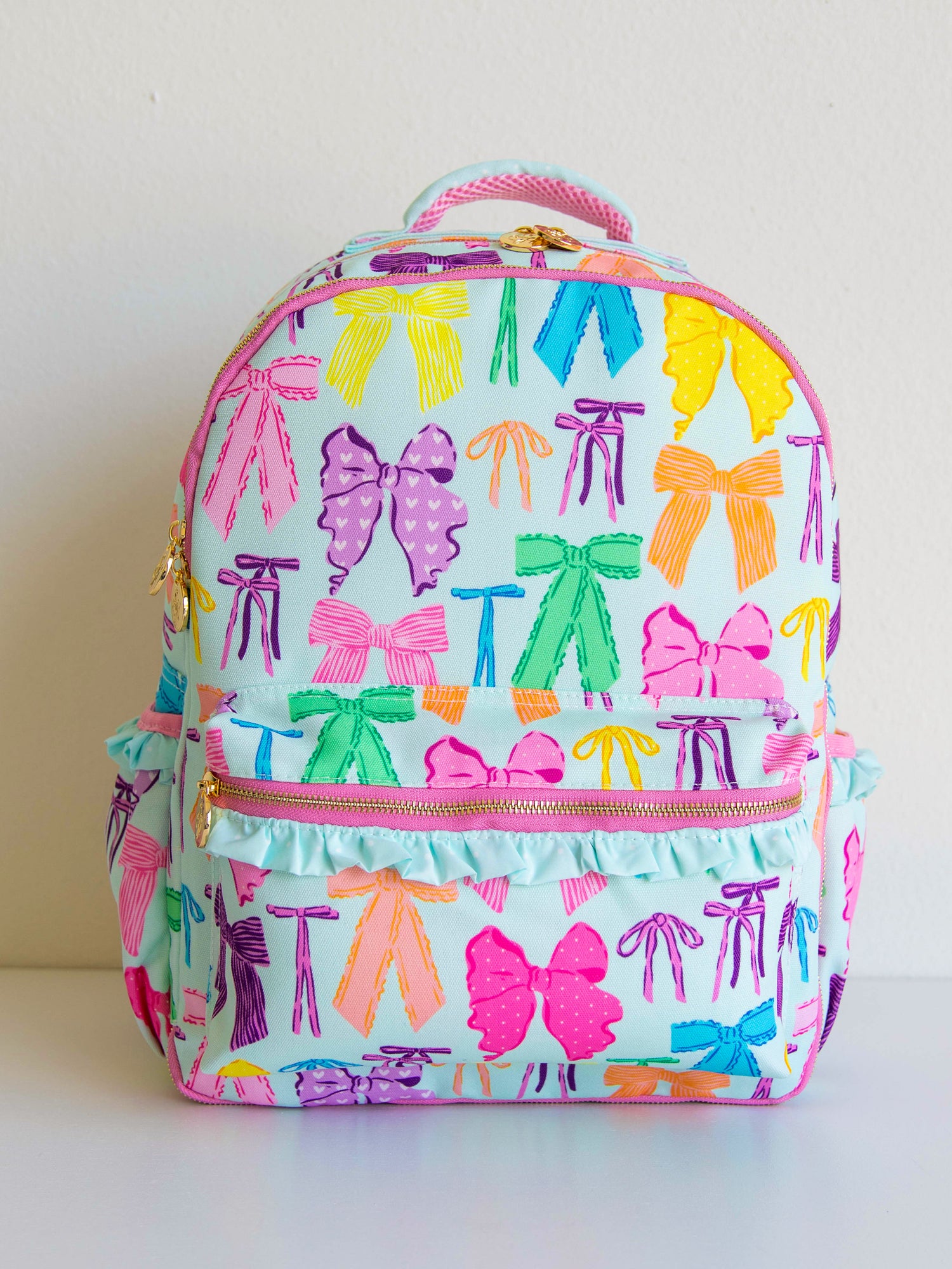 Vibrant bows printed backpack with customized embroidery, gold zippers and zipper pulls, and a handle