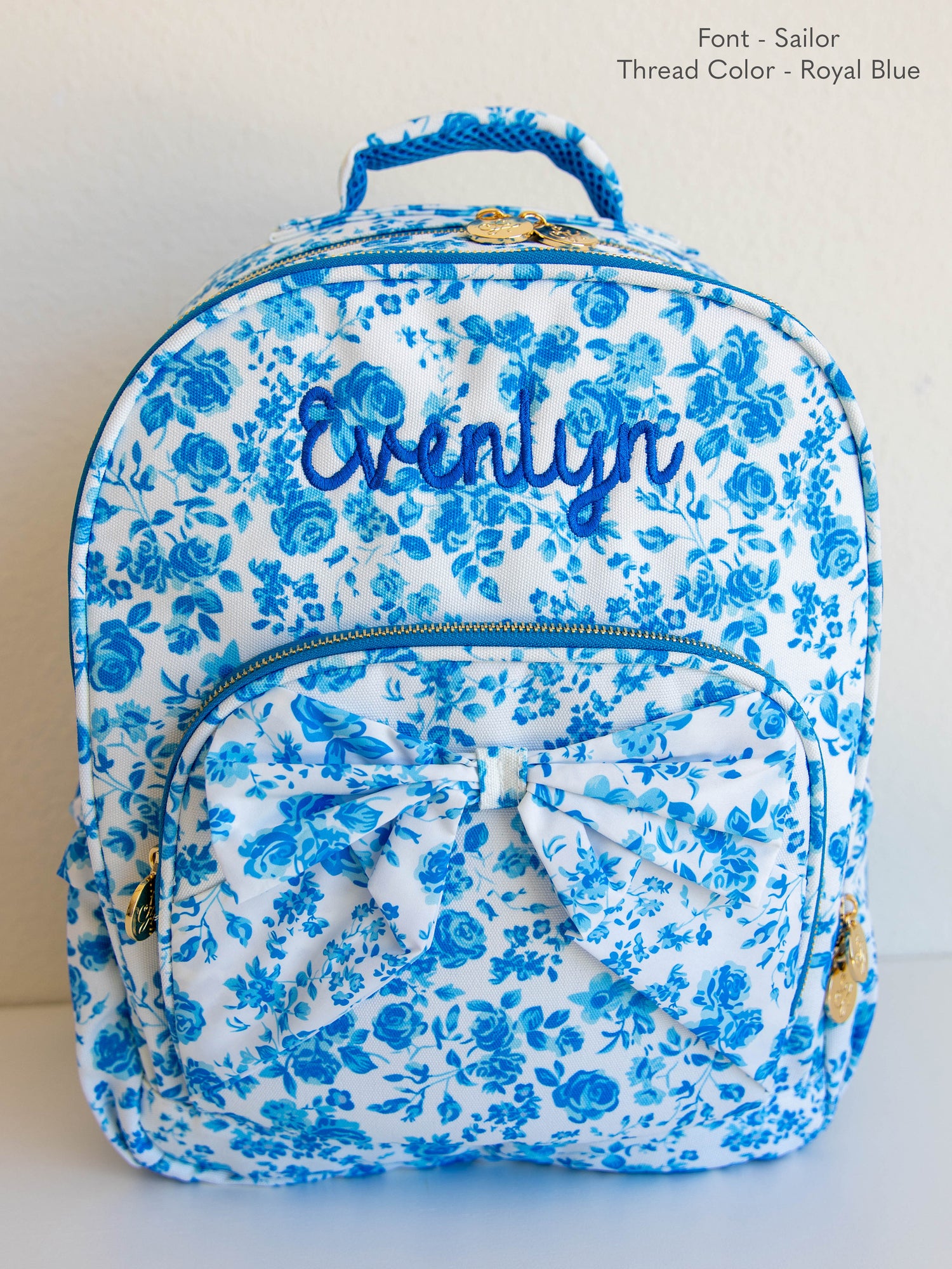 Blue floral backpack with attached bow on front pocket and customized embroidery 