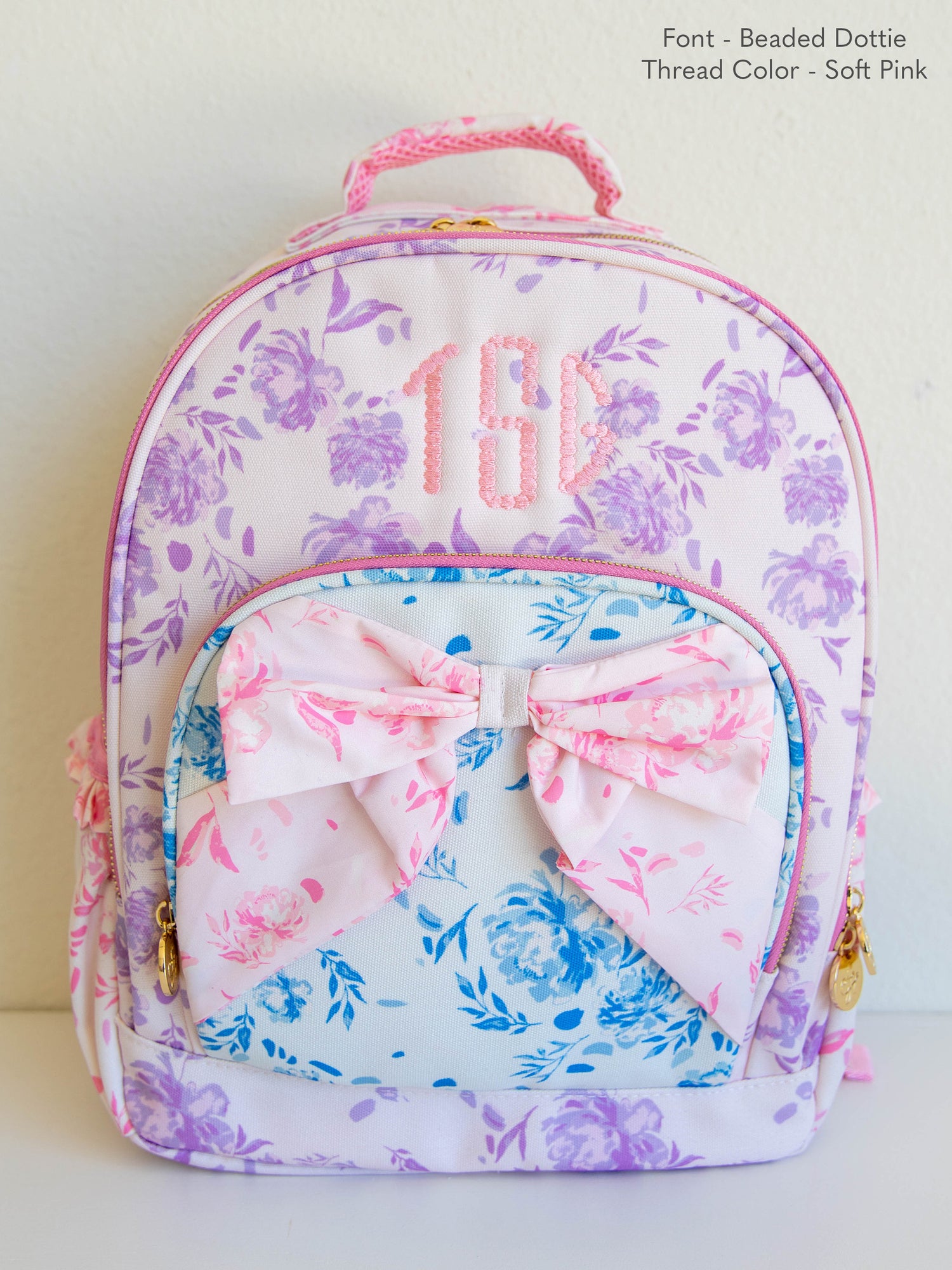 Backpack with floral prints and a bow on the front. Picture shows custom embroidery on front. 
