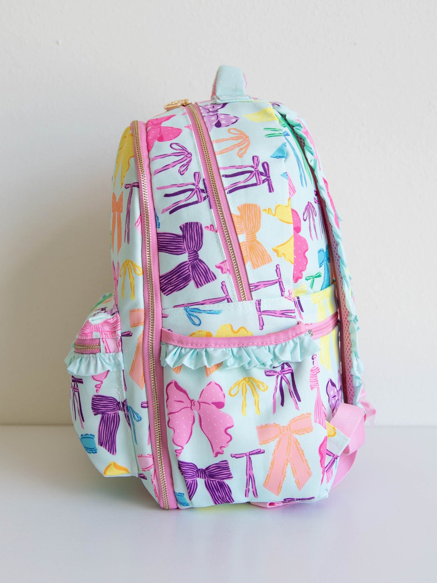 Vibrant bows printed backpack with customized embroidery, gold zippers and zipper pulls, and a handle