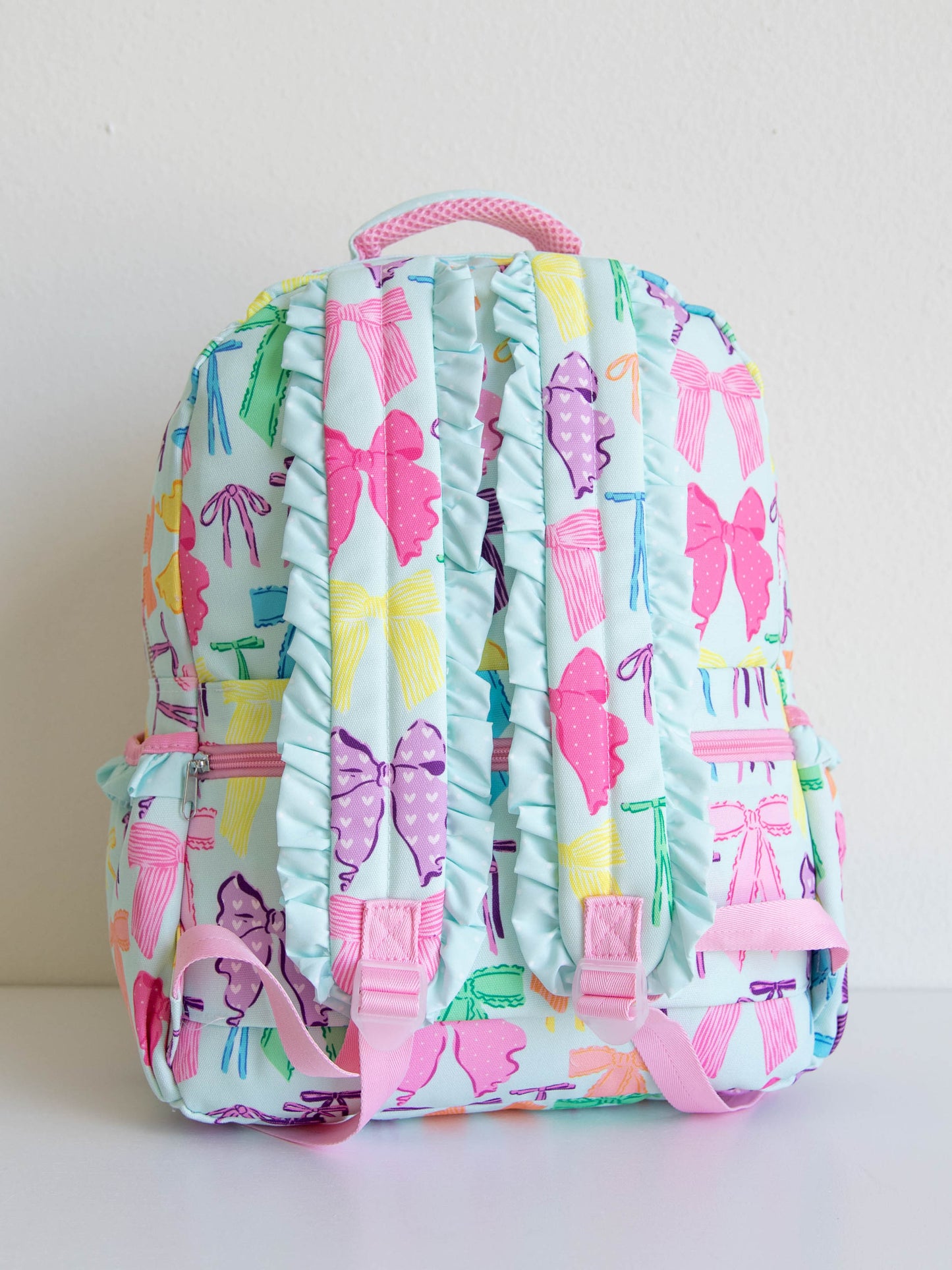 Back of Vibrant bows printed backpack showing the ruffled back staps