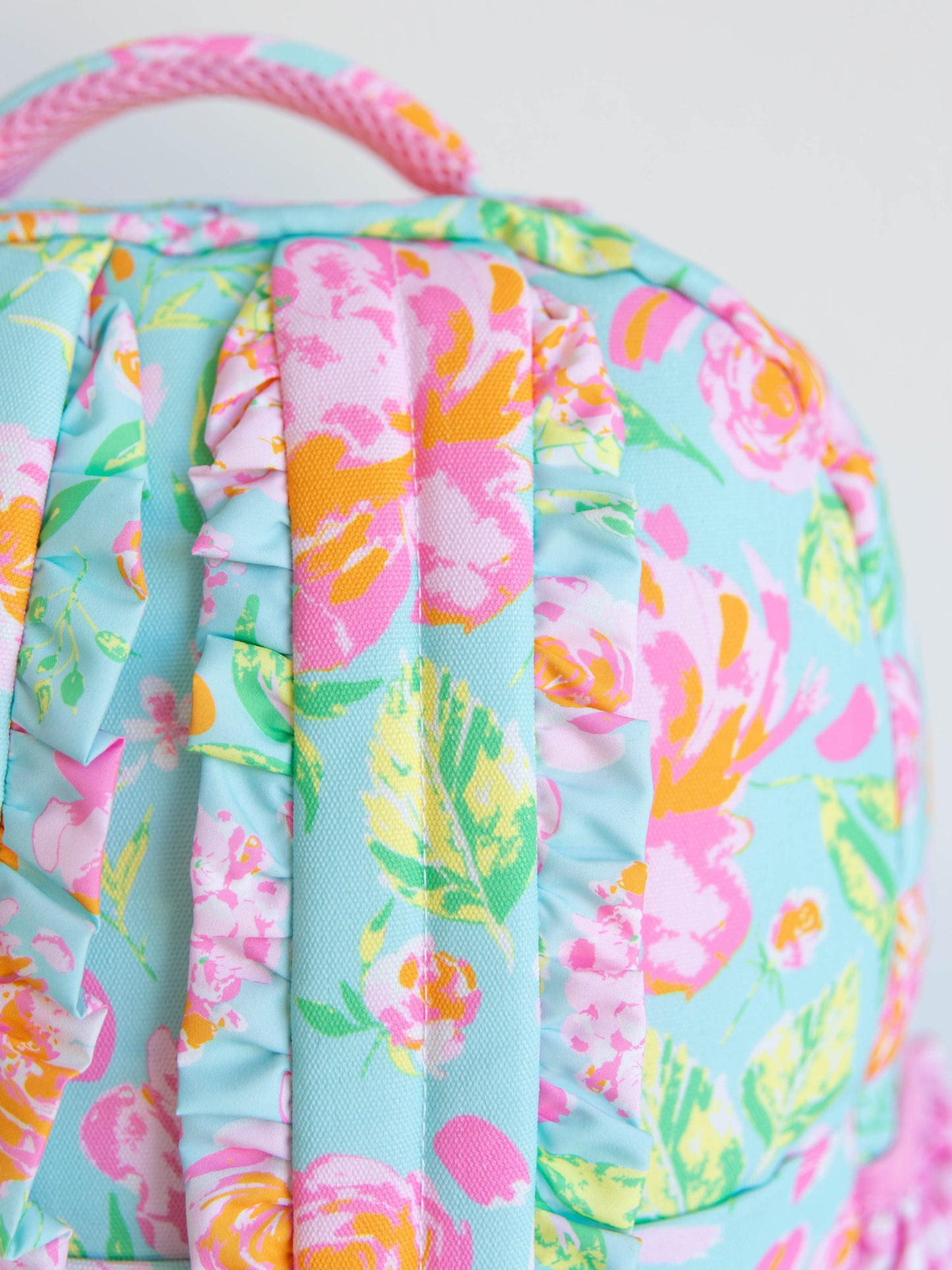 Colorful and floral backpack showing the ruffled straps at back and handle on top