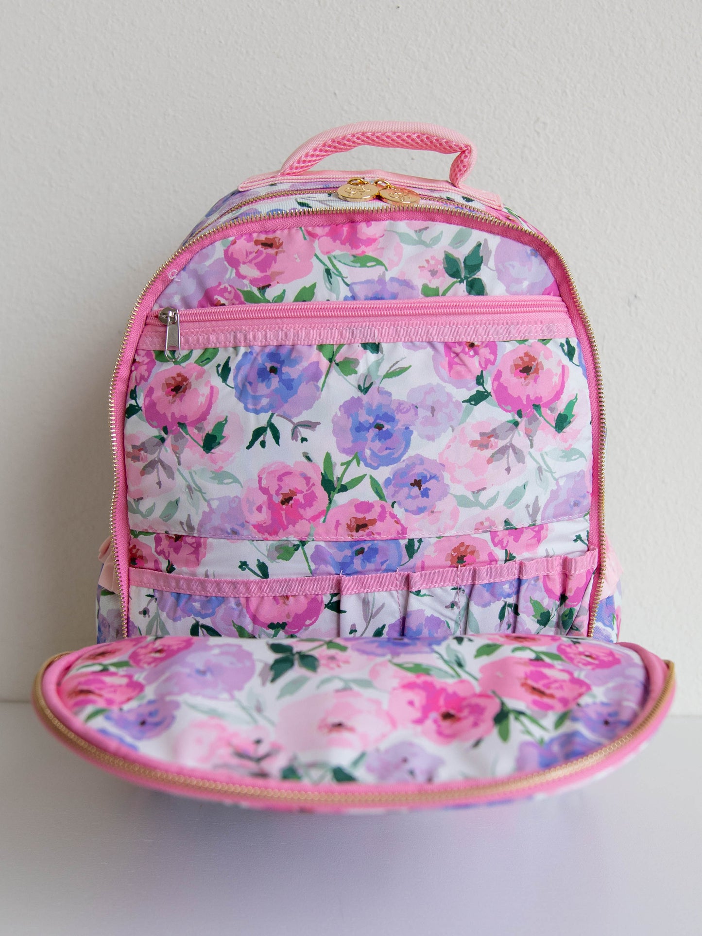  colorful floral backpack with a purple gingham bow attached to the backpack. gold zippers and zipper pulls. 