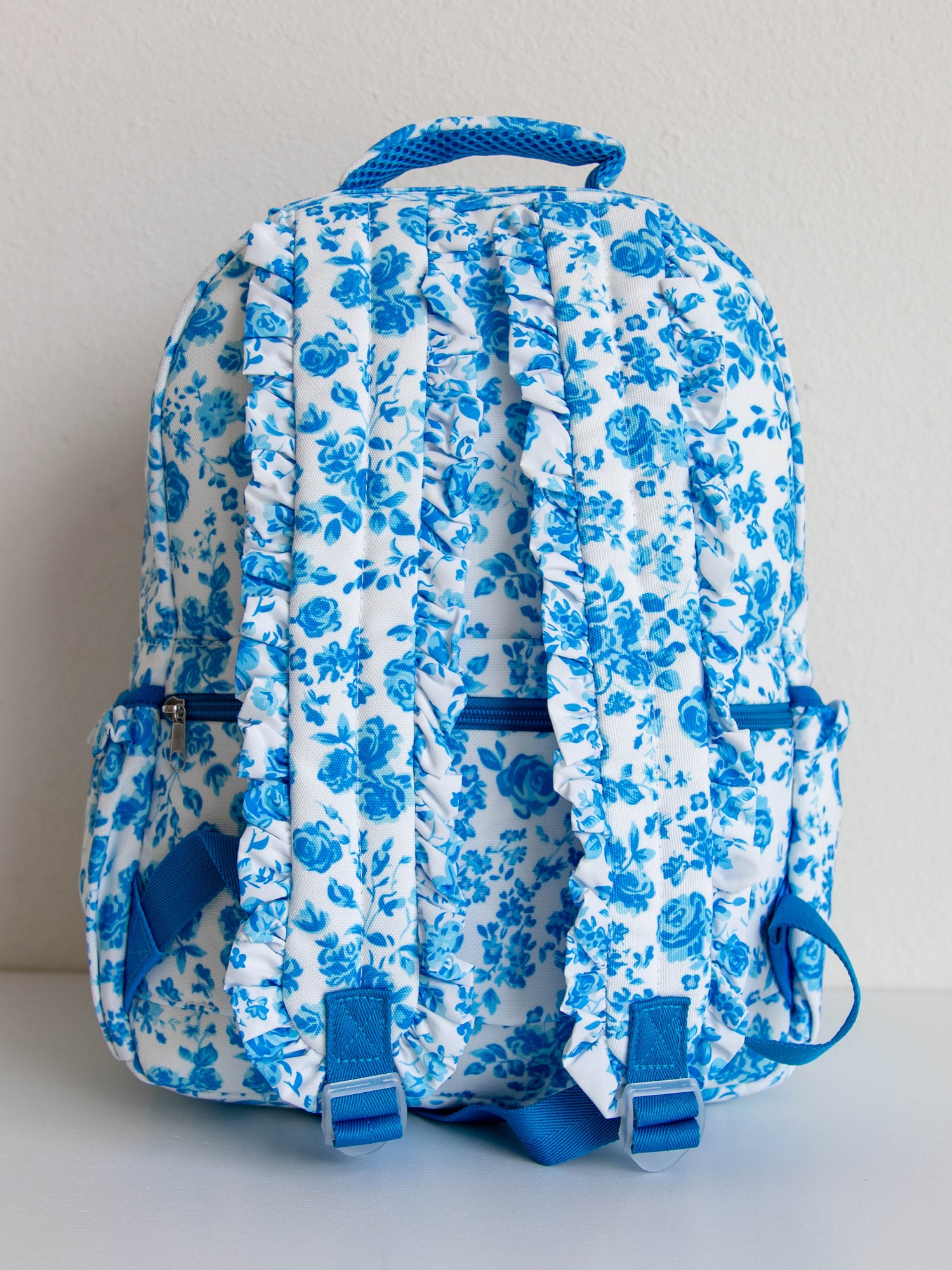 Back of blue floral backpack that shows ruffled straps