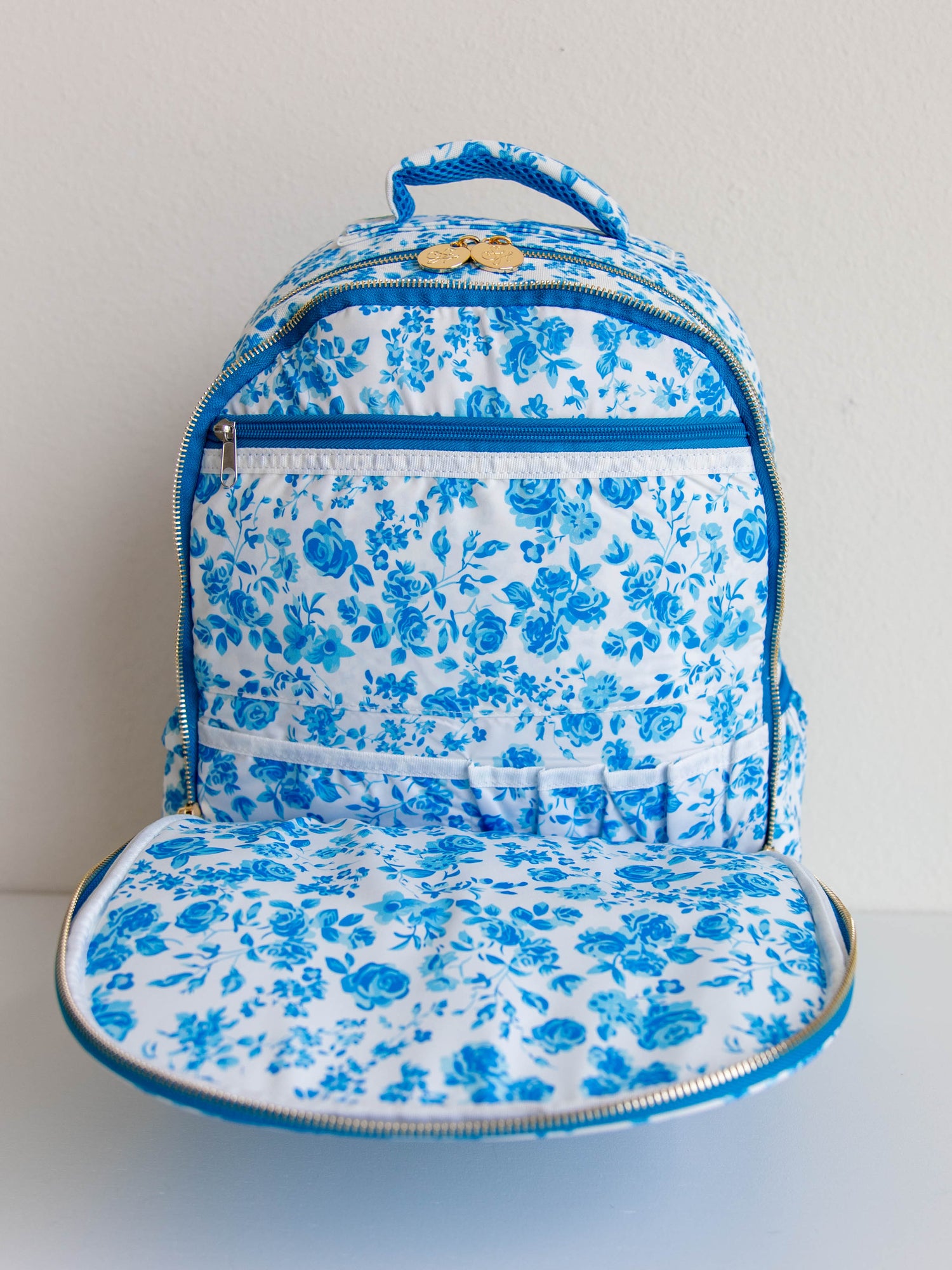 Blue floral backpack with front flap open to show storage compartments