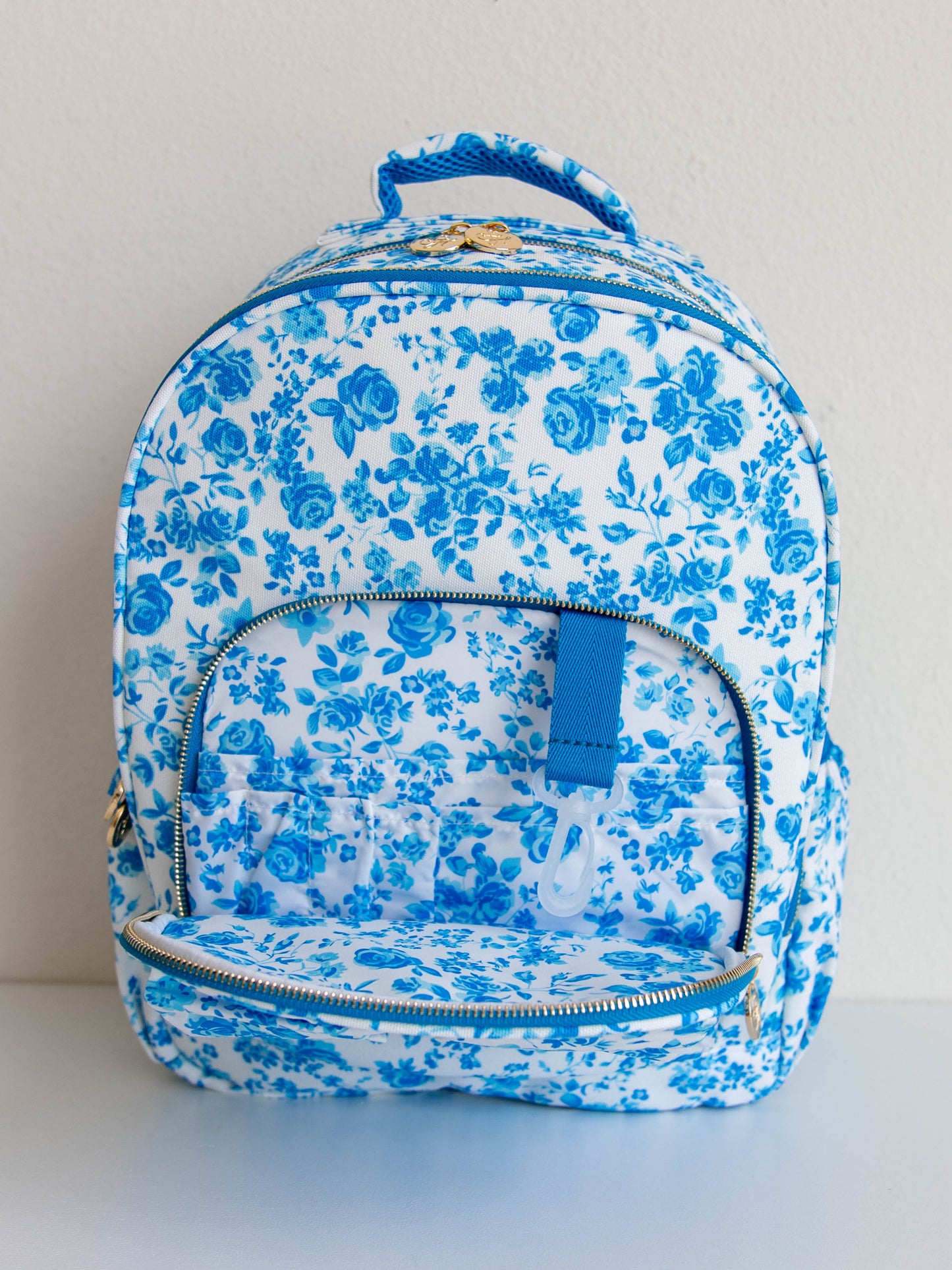 Blue floral backpack with front flap open to show storage compartments