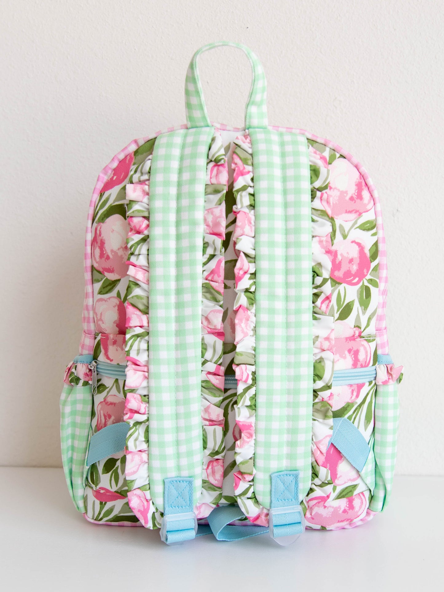 Ruffled straps on the back of a floral and colorful backpack
