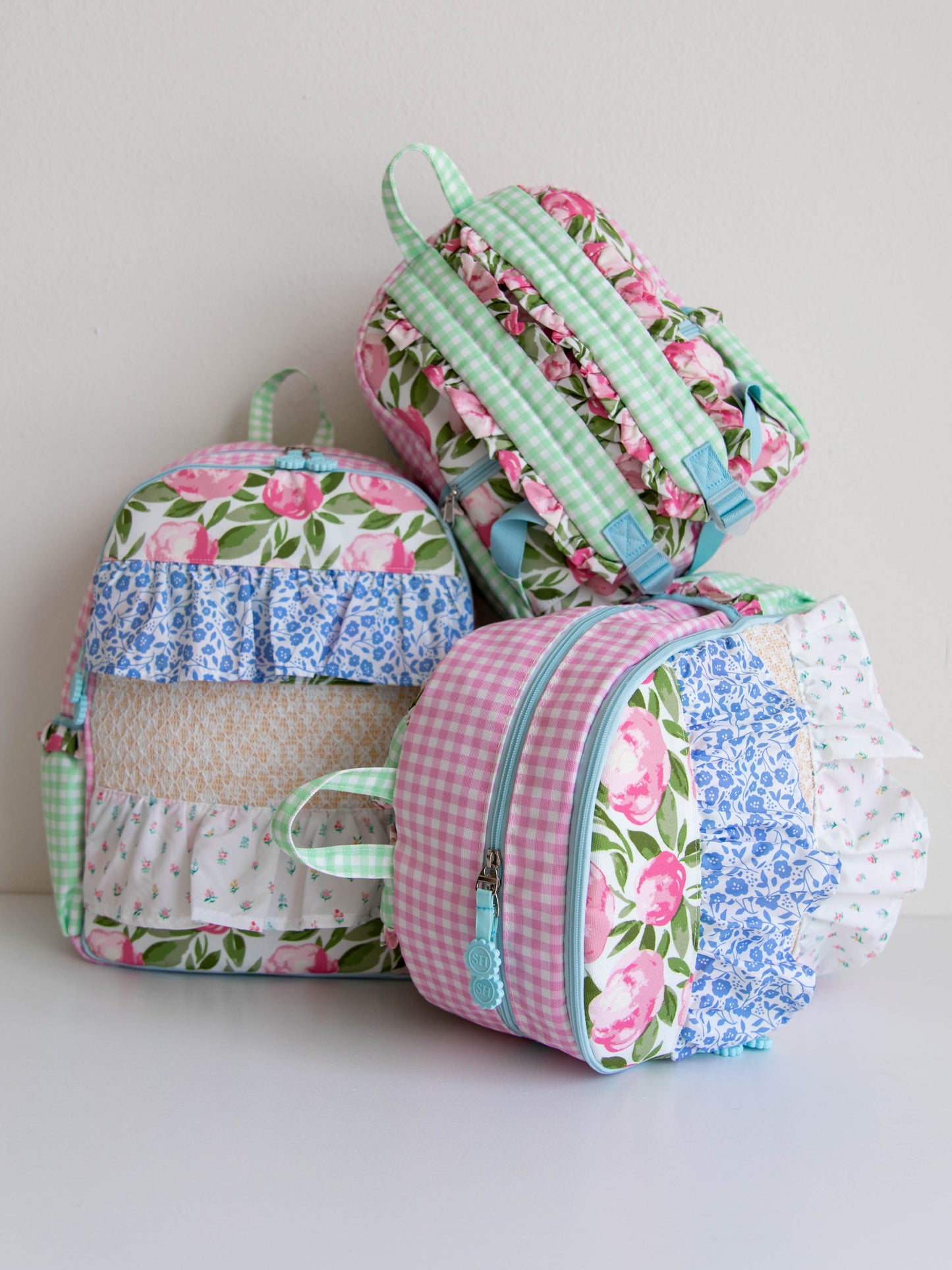 Stack of 3 different sized, colorful floral backpacks