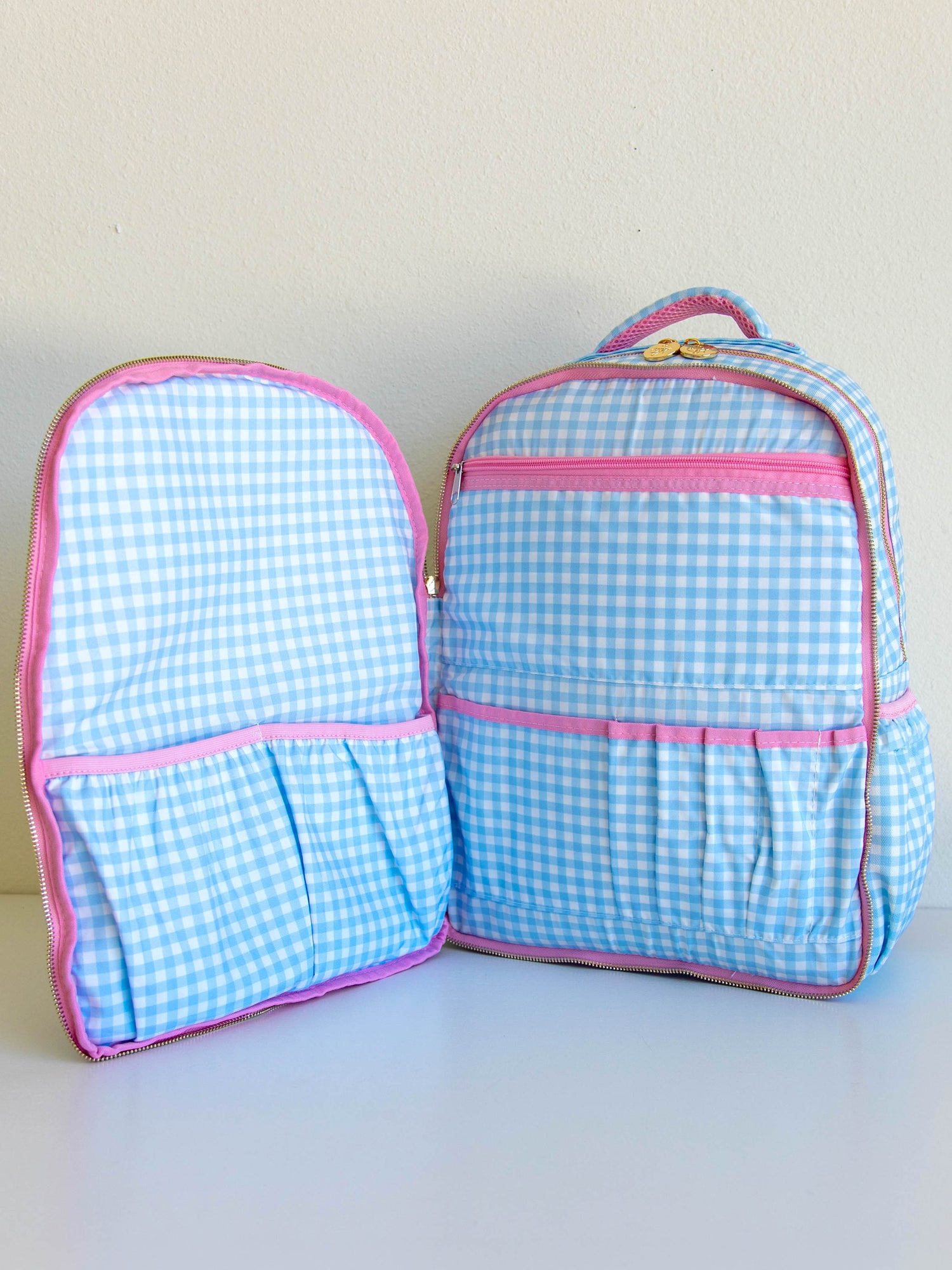 Blue gingham backpack opened up to show different storage compartments. 