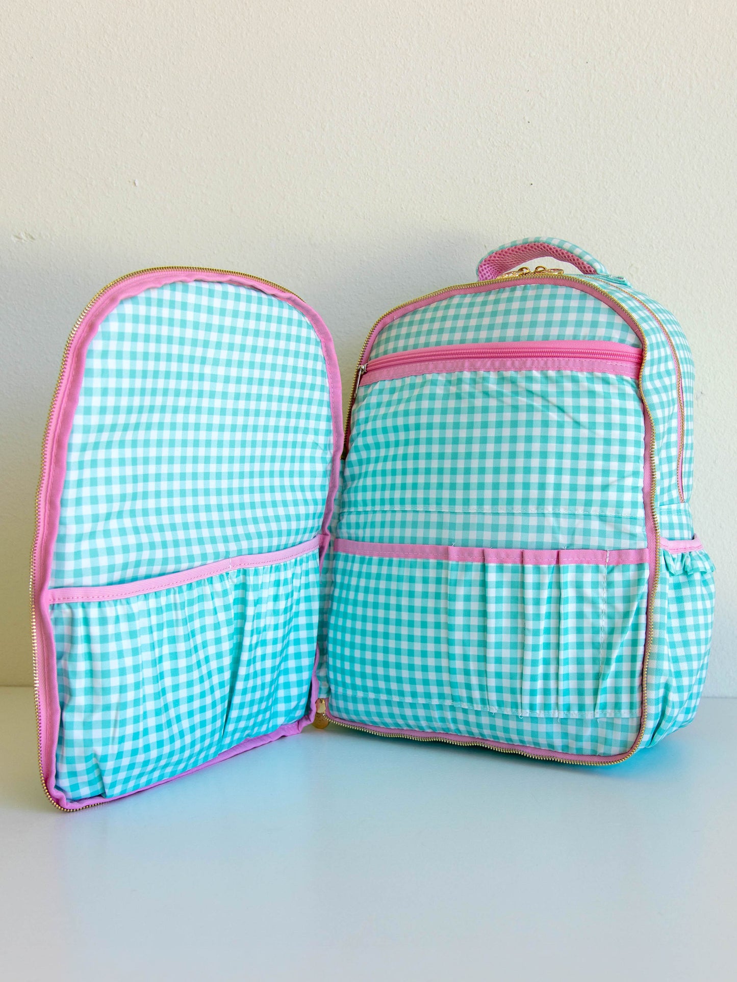 mint green gingham backpack with front zipper pocket open to show different organization pockets, etc
