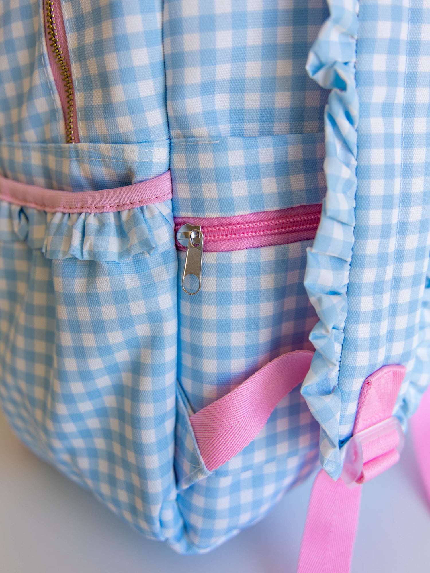 Close up of blue gingham backpack showing zipper to trolly sleeve