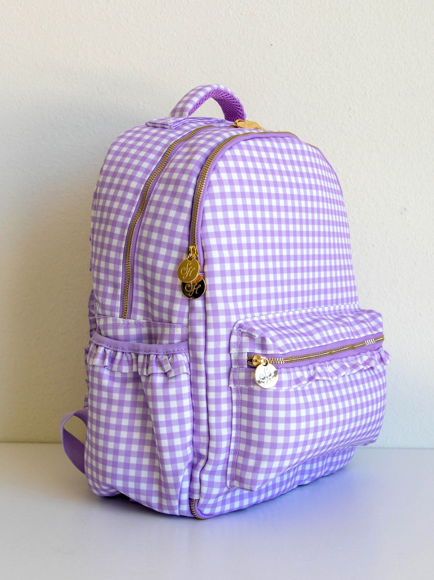 Single purple gingham backpack at a side angle that shows gold zipper pulls