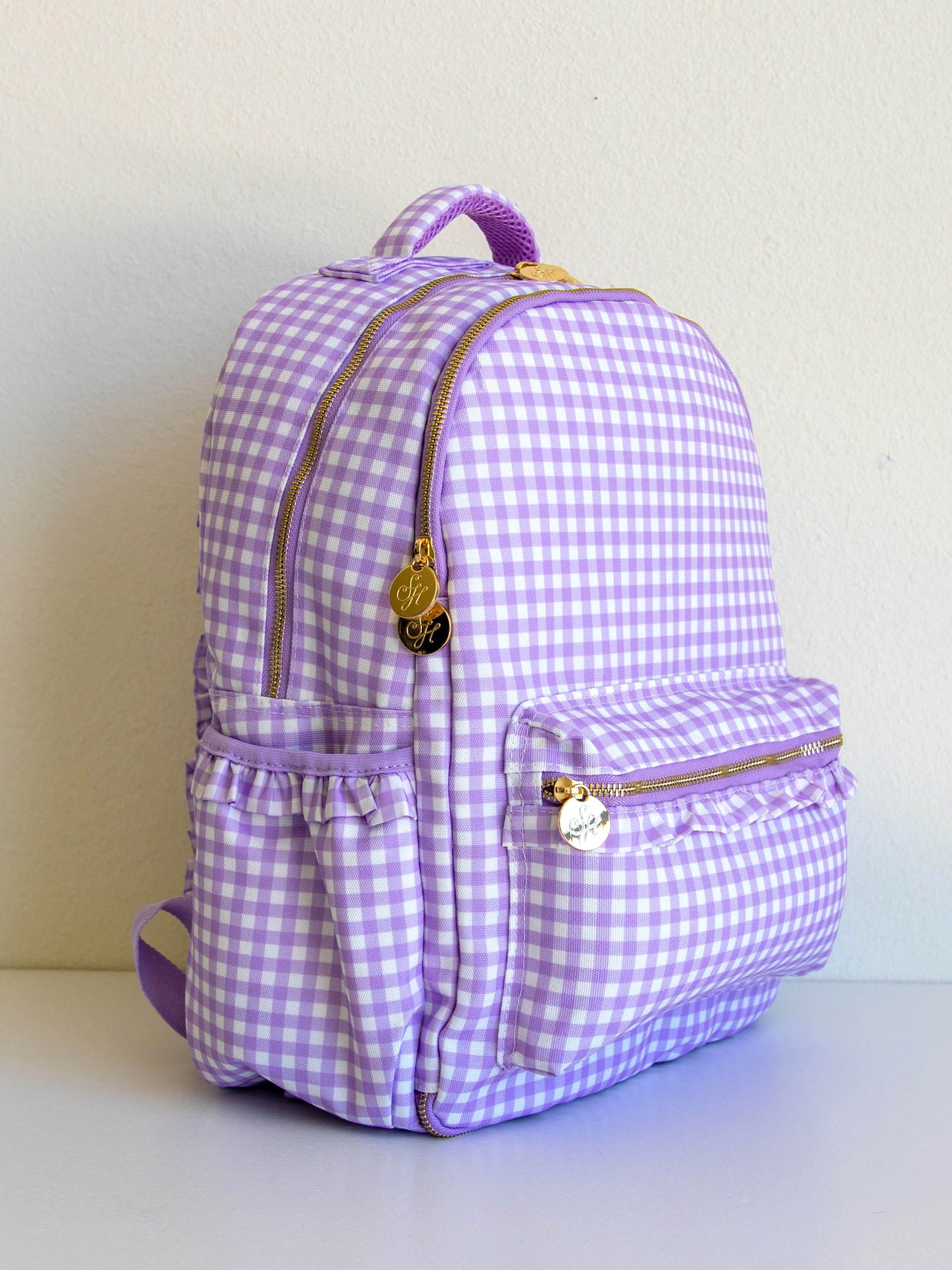 Single purple gingham backpack at a side angle that shows gold zipper pulls