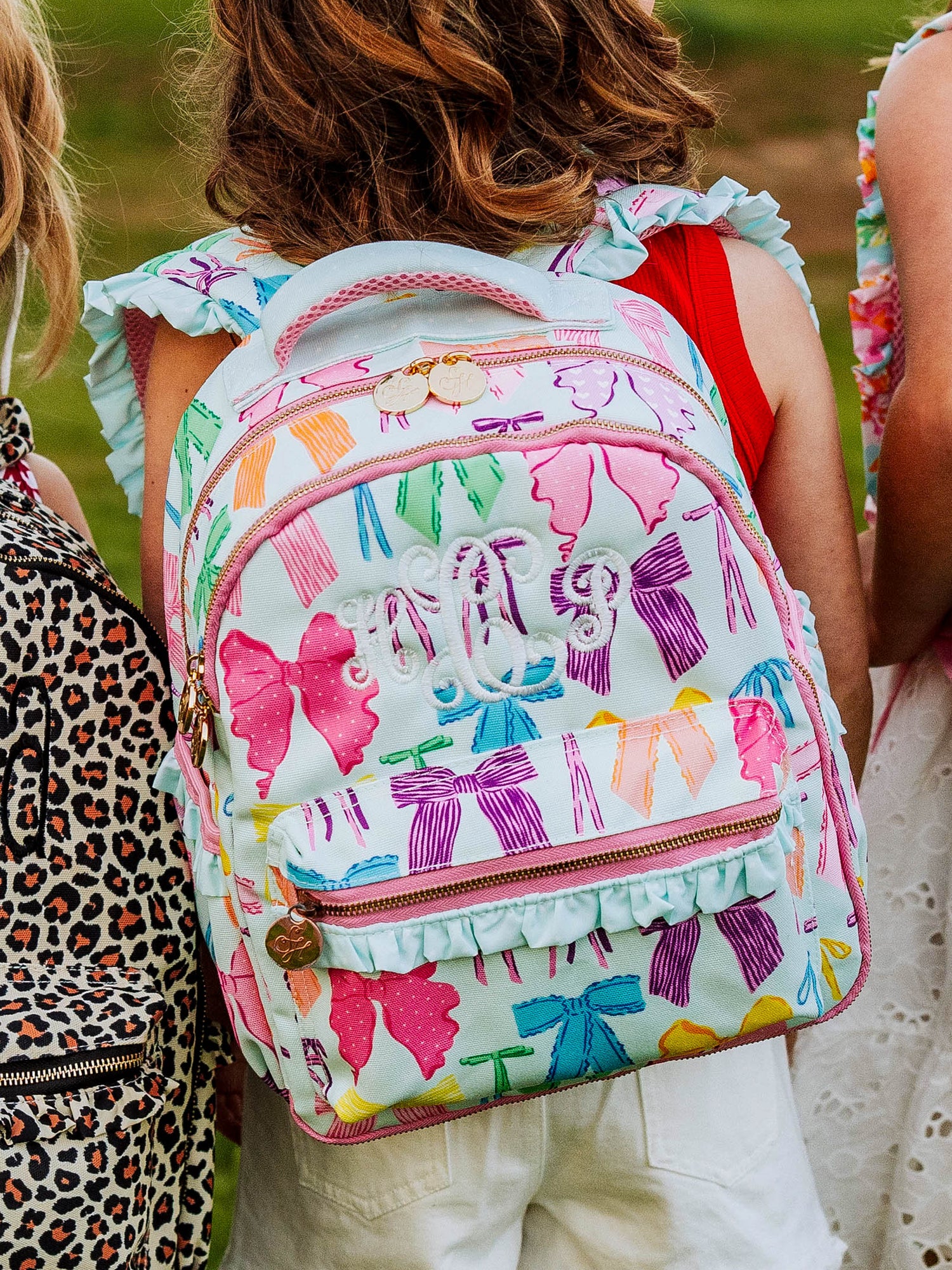Girl wearing a custom embroidered backpack with a vibrant bows print