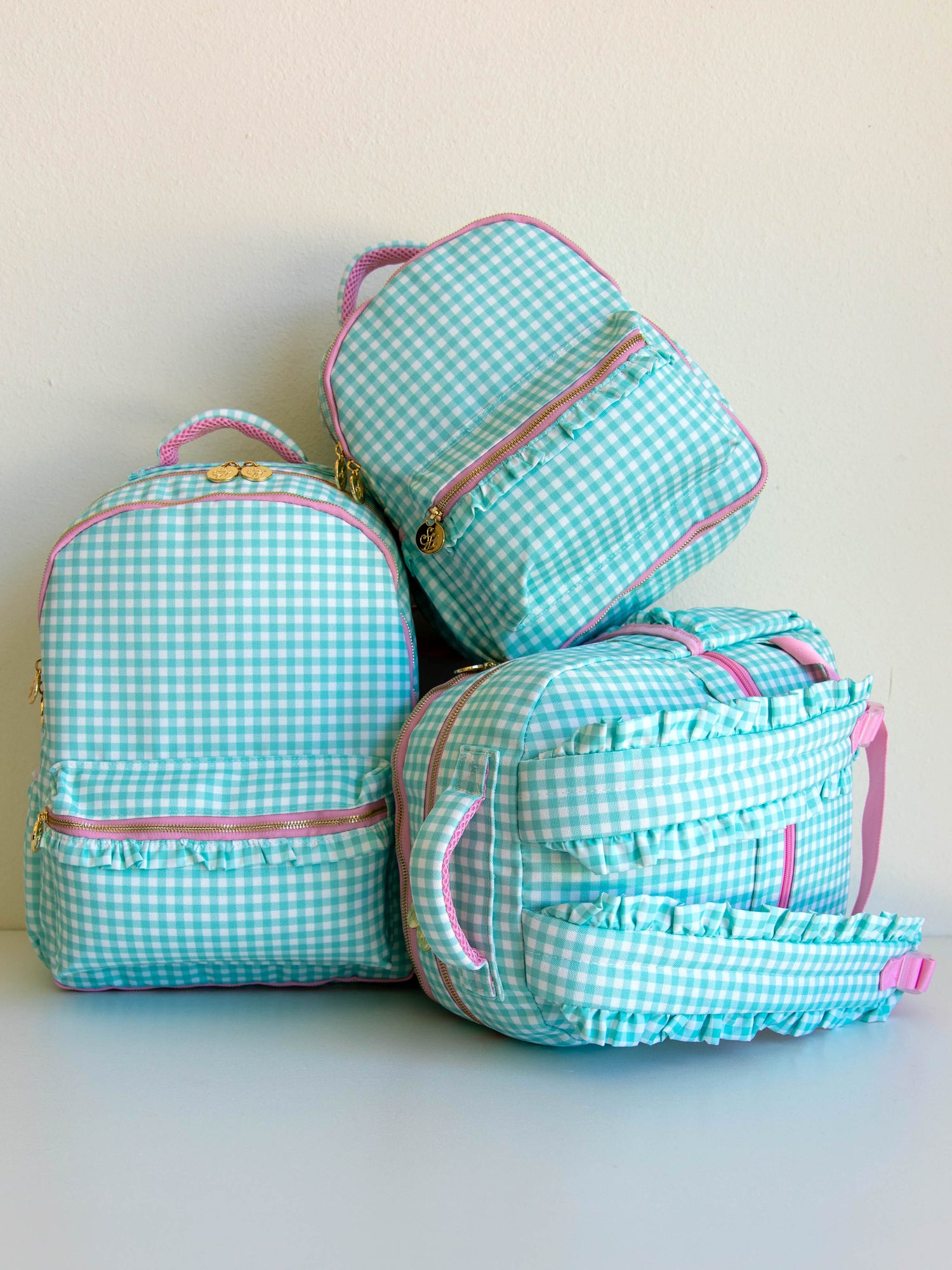 Three different sized mint green backpacks stacked in different ways. 