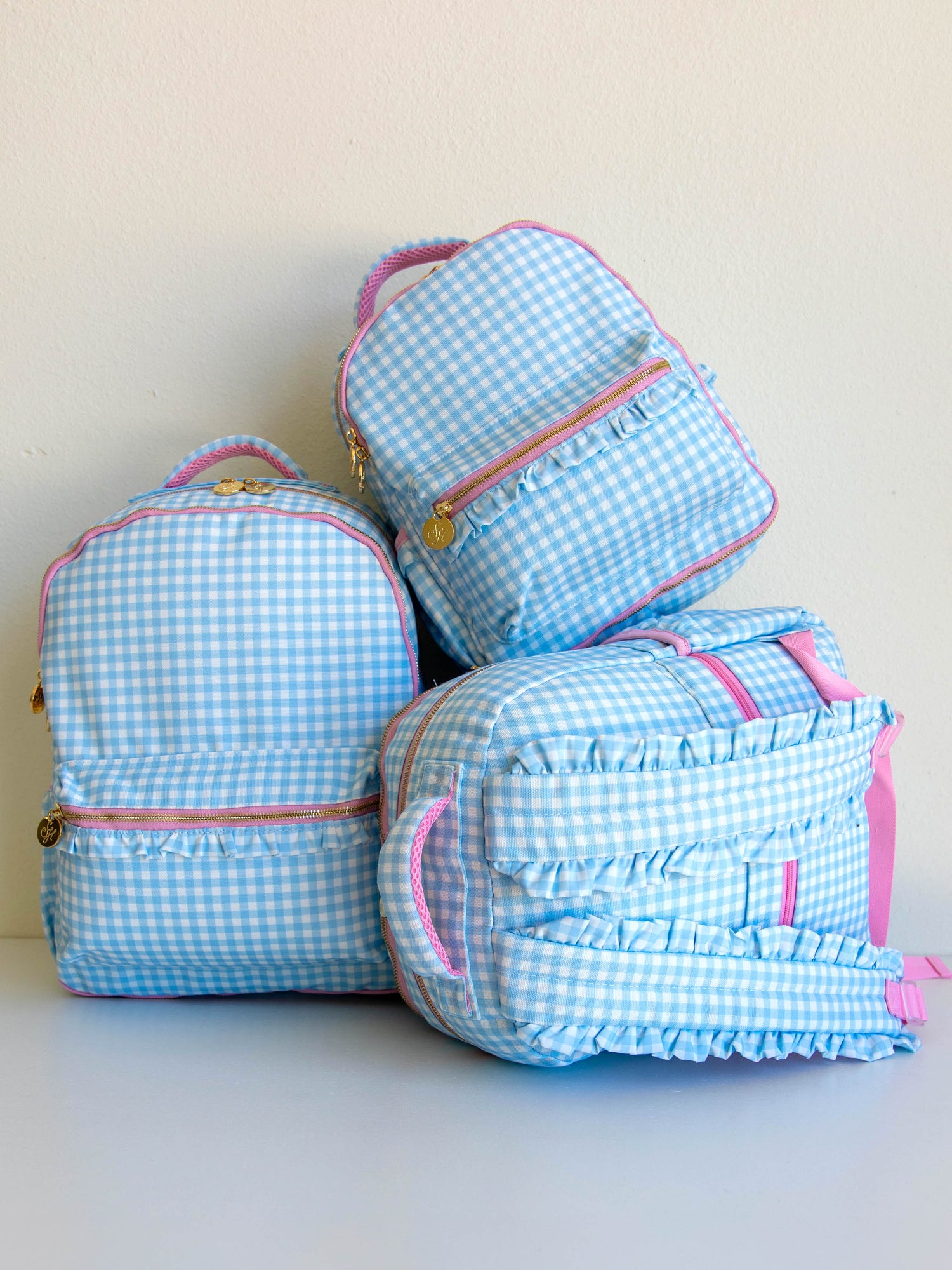Picture of 3 different sized, blue gingham backpacks.