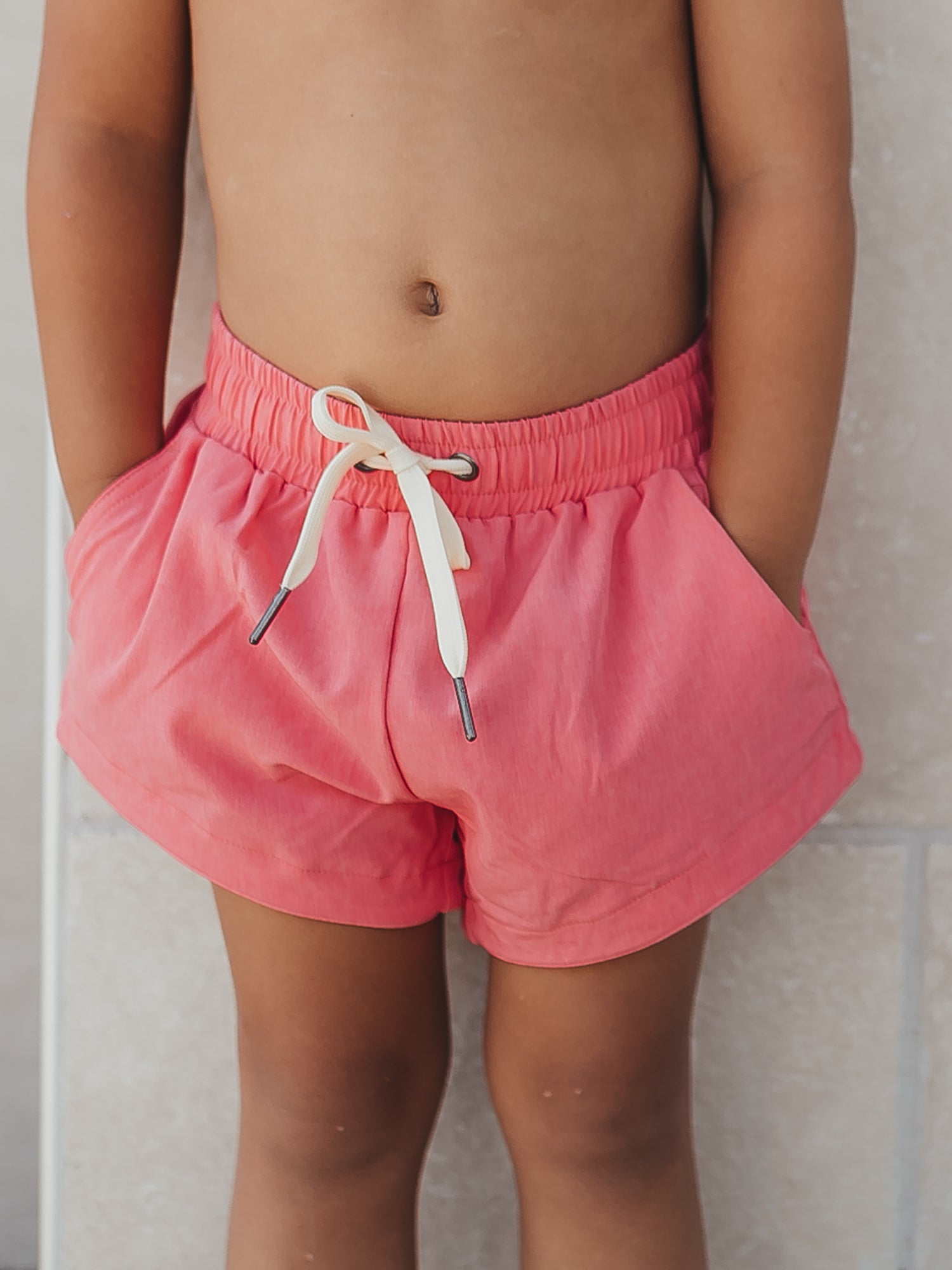 This image of a boy features the European cut style of our Boy's Everyday Lined Trunks – Magenta Solid