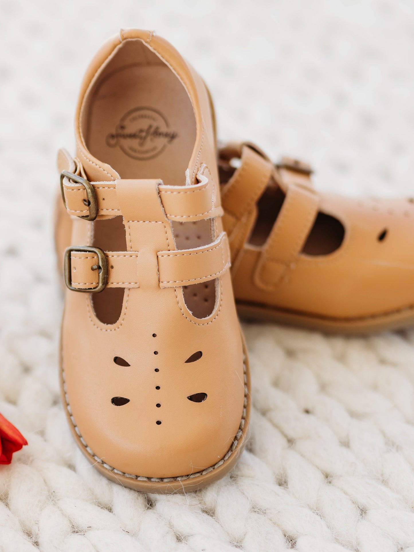 A pair of tan colored genuine leather rubber soled shoes with two adjustable metal buckles and cut out detail across the toe area in a dragonfly type pattern. 