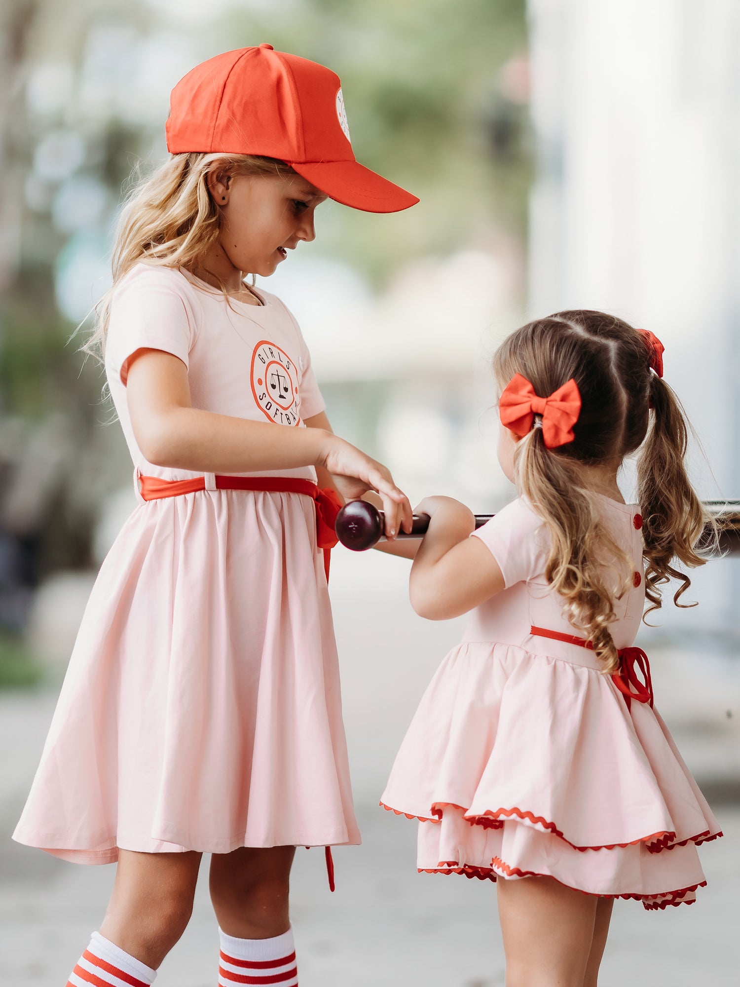 This image of a girl features the product Belle Bubble - Girls Softball. This pink double skirted dress has the same Girls Softball logo on the front as our Girl’s Softball Dress & Hat.