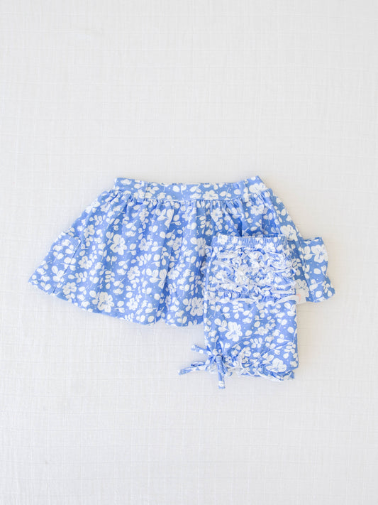 Garden Skirt and Bloom Set – Blooming Petals. It comes in a pattern of off-white flowers and petals on a warm blue background.
