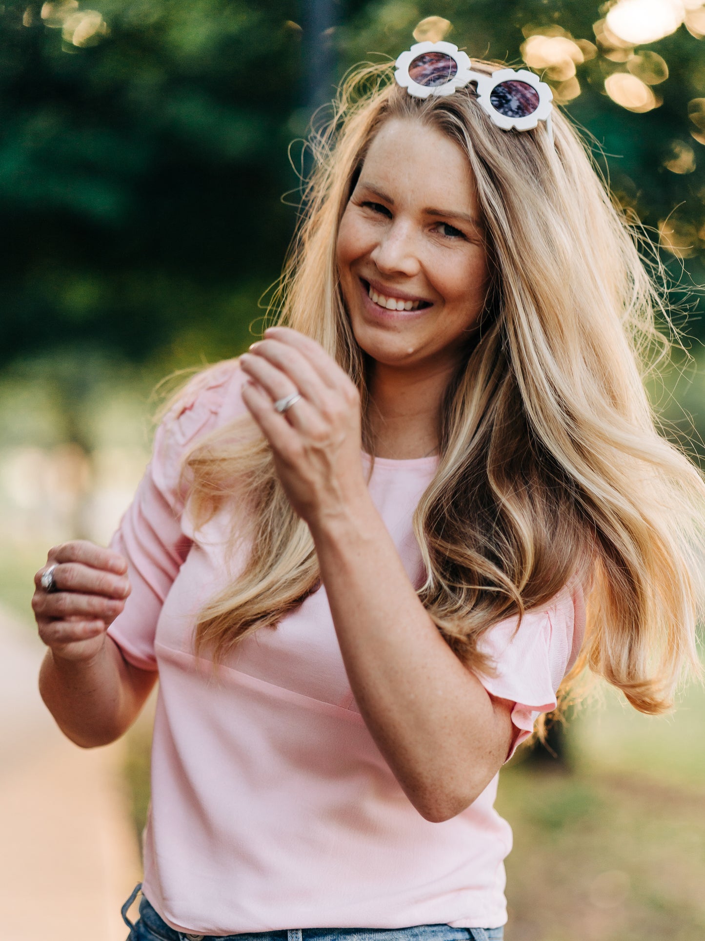 This image of a woman features the product Classic Smocked Cutout Top – Soft Pink. This short sleeve top has a smocked and keyhole back, and synched sleeves. 