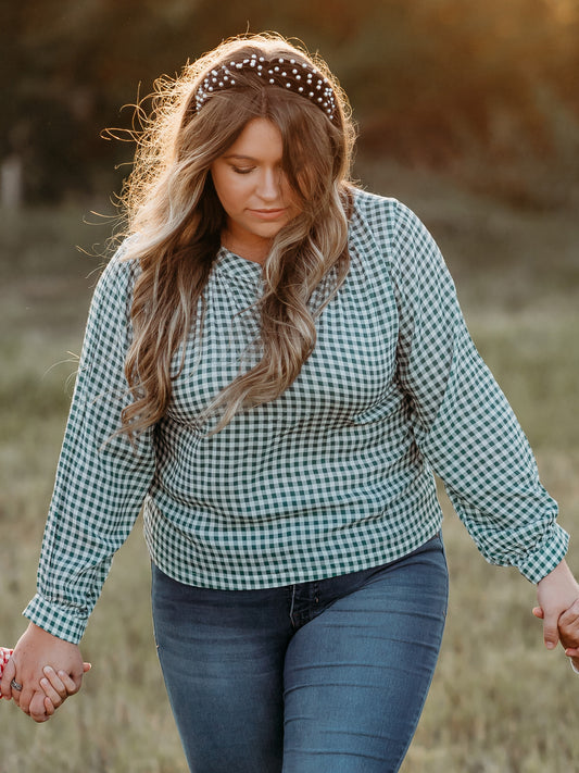 This image of a woman features the product Women's Long Sleeve Blouse - Mistletoe Check. This long-sleeved blouse comes in a blue/green and white check pattern.