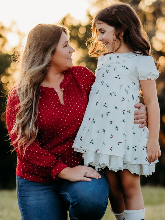 This image of a woman features the product Women's Long Sleeve Blouse - Christmas Dotty. This long-sleeved blouse comes in a pattern of white polka dots on a red background.