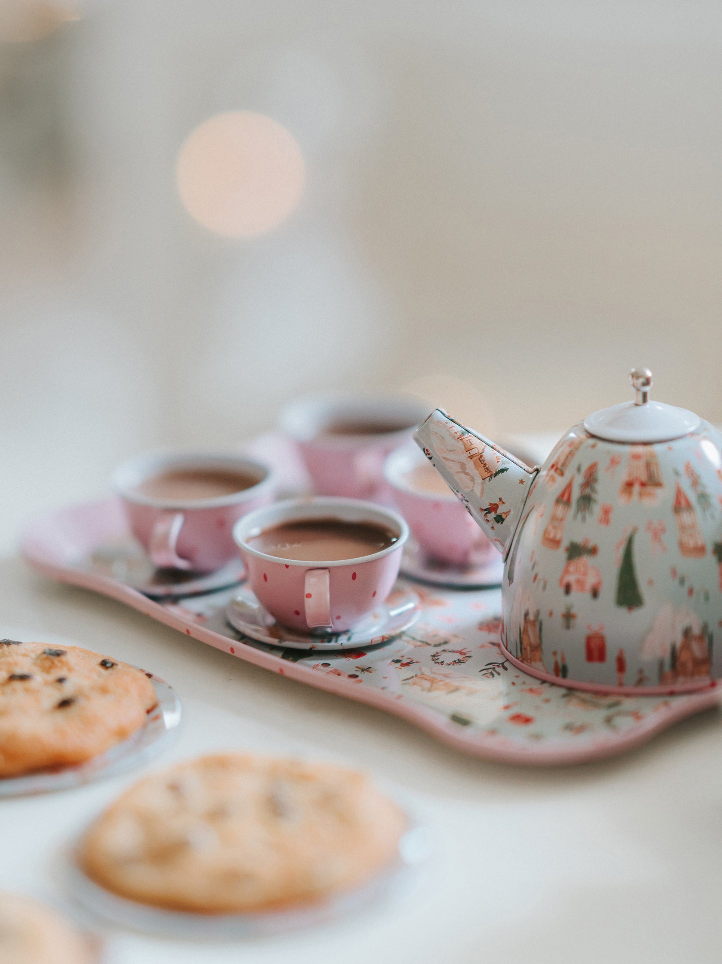 The serving tray, plates, and kettle features our pattern Christmas Village. The cups are a pattern of pink polka dots on light pink.