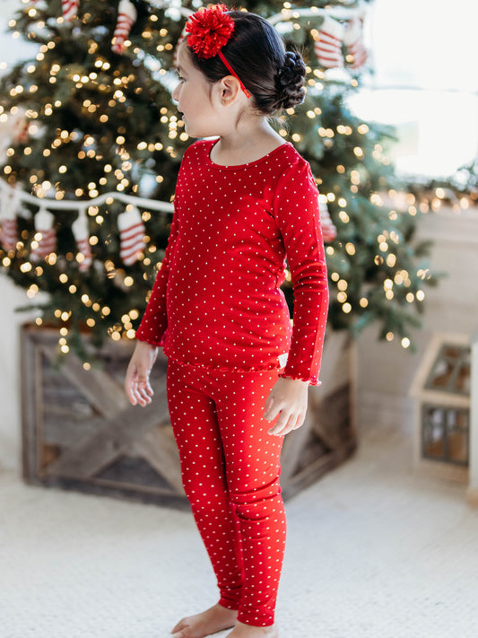This image of a girl features the product Frilled Sleeve Set - Christmas Dotty. The long sleeve set comes in a pattern of white polka dots on a red background.