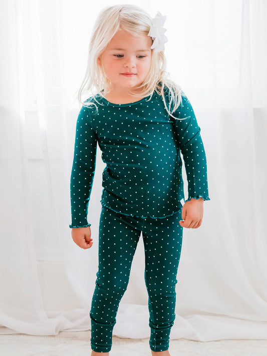 This image of a girl features the product Frilled Sleeve Set - Christmas Dotty. This long sleeve set comes in a pattern of white polka dots on a deep blue green background.