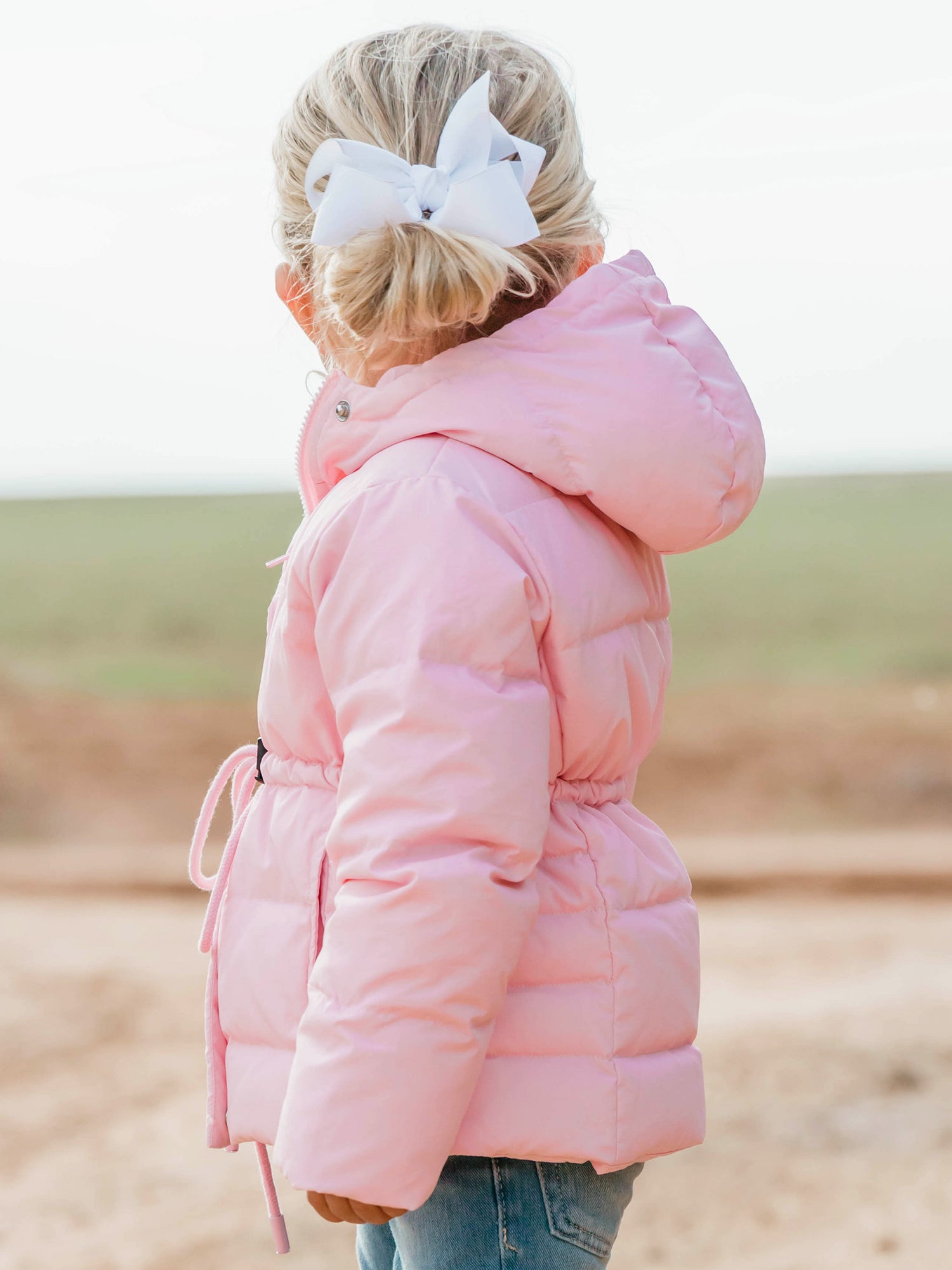 Keep her cozy and cute all season long in our Pink Puffer Jacket — the perfect blend of warmth and style! This soft, quilted jacket features a full zipper closure with a button placket, ensuring extra protection from chilly winds. Hidden front pockets keep little hands warm (or treasures tucked away), while the adjustable waist toggle allows for the perfect, comfortable fit. Designed in a beautiful blush pink hue, this girls’ puffer jacket pairs effortlessly with any winter outfit for a look that's fun!