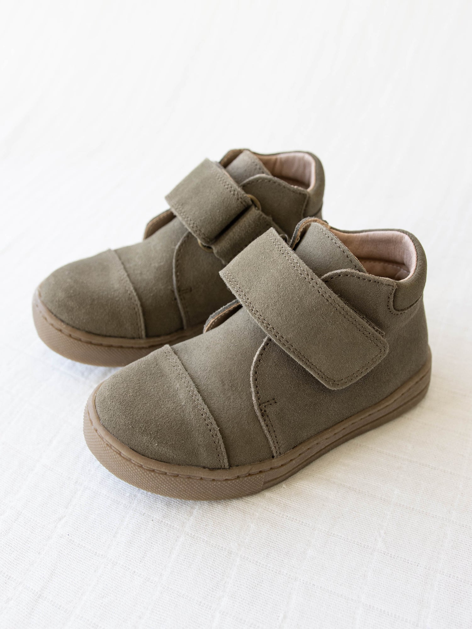 This Suede Mid Boot comes in a Sage color with a brown rubber sole and wide velcro strap across the top of the foot.