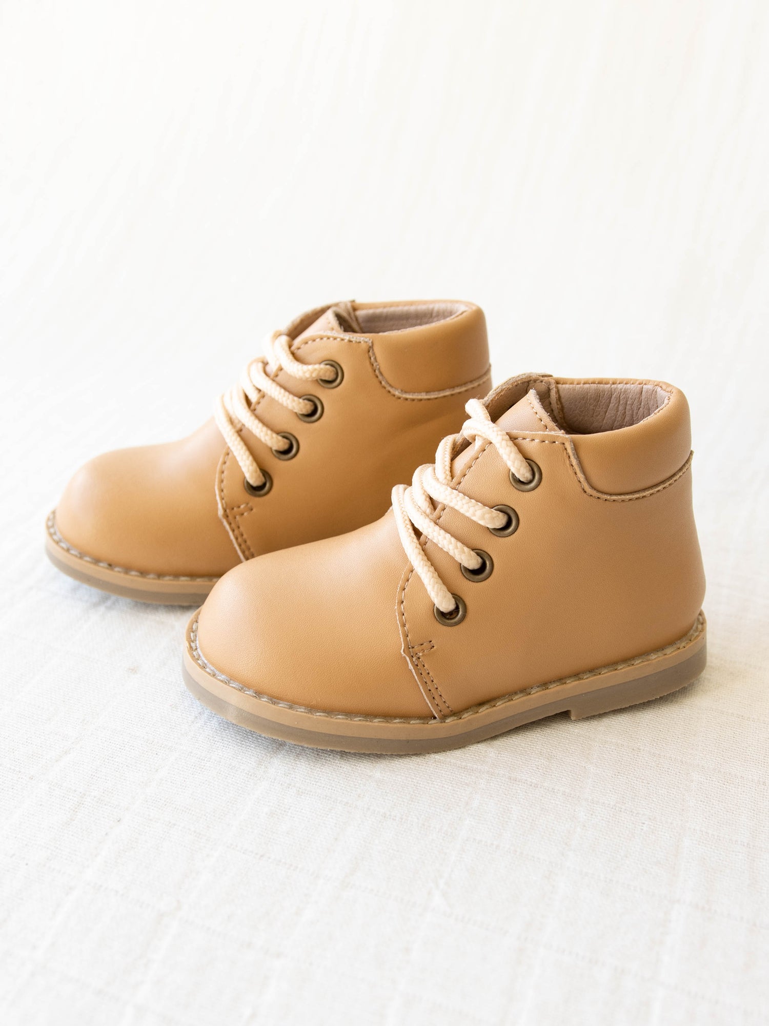 Pair of tan manmade leather Lace Up Ankle Boots with metal grommet eyelet holes and rubber soles. 