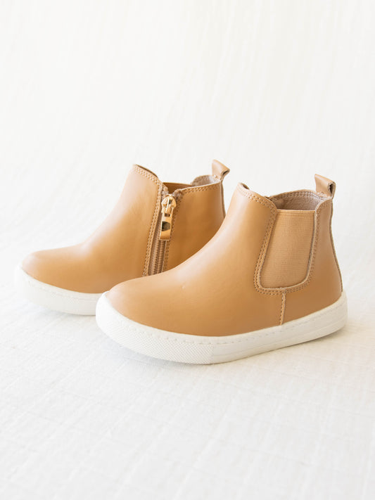 Chelsea Sneaker is a tan shoe with a side zipper on one side and some elastic on the other.