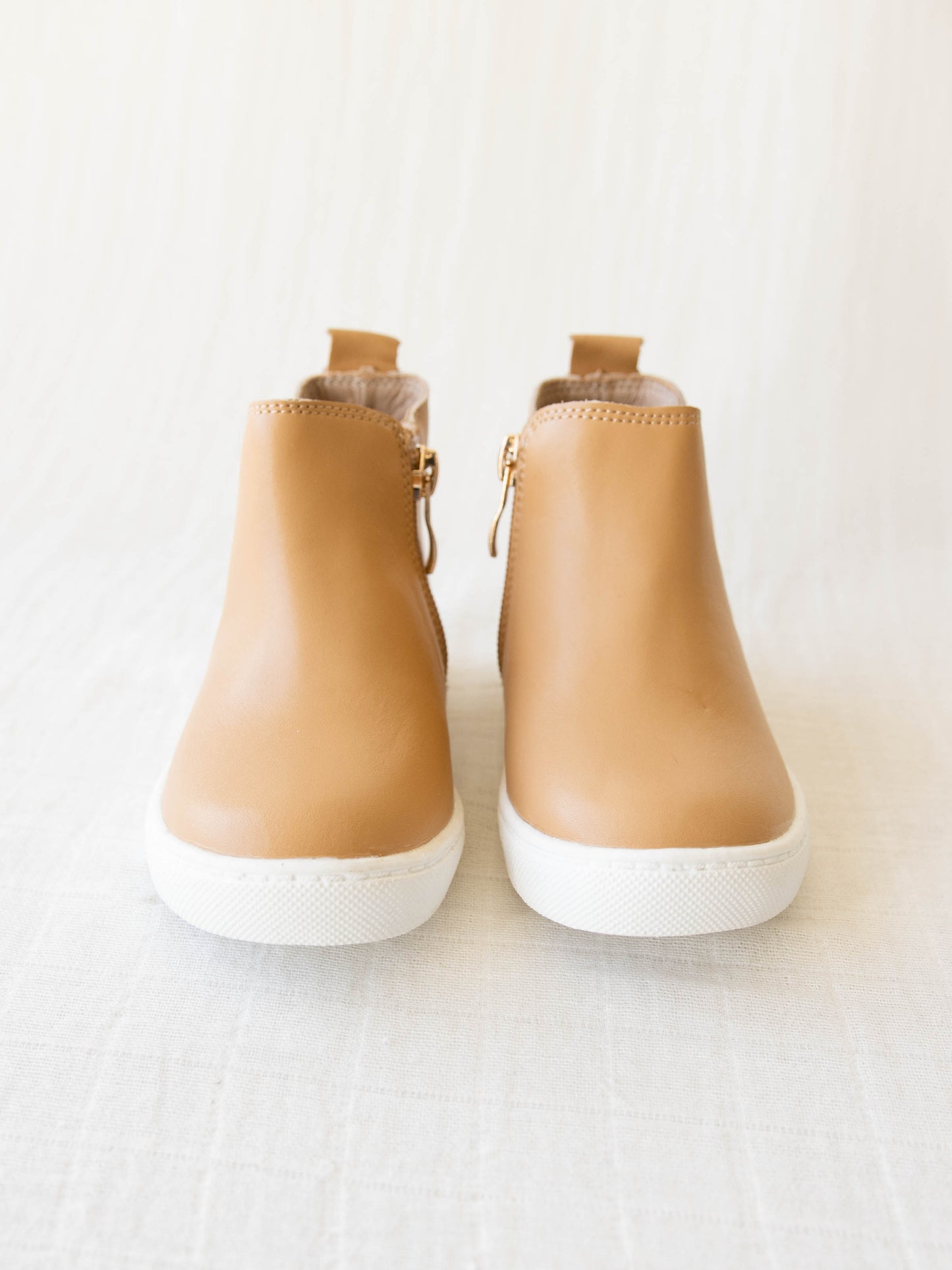 Chelsea Sneaker is a tan shoe with a side zipper on one side and some elastic on the other.