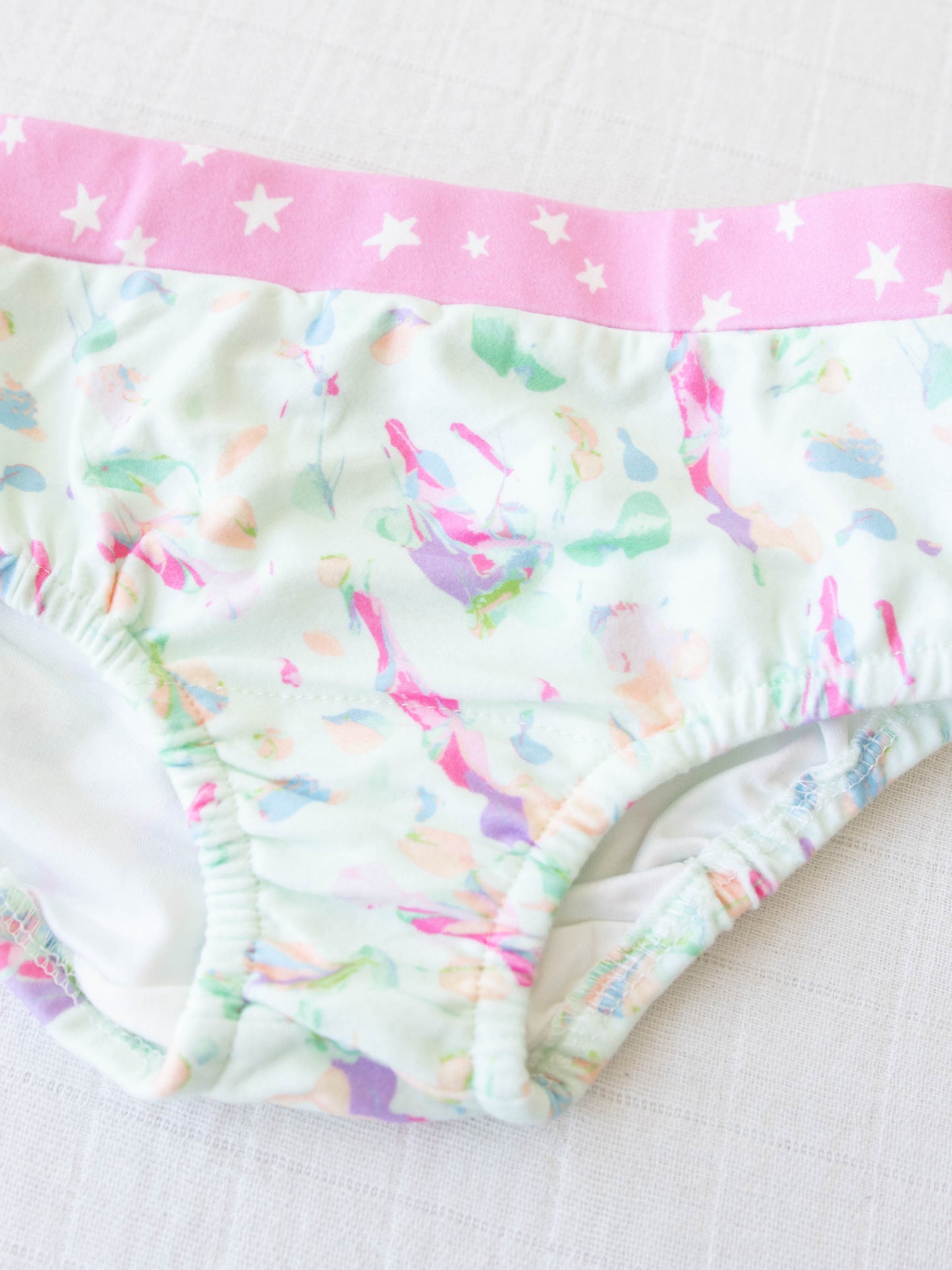 On this pair of girls panties we have a fun paint splatter effect of many colors over a light blue-green color. 