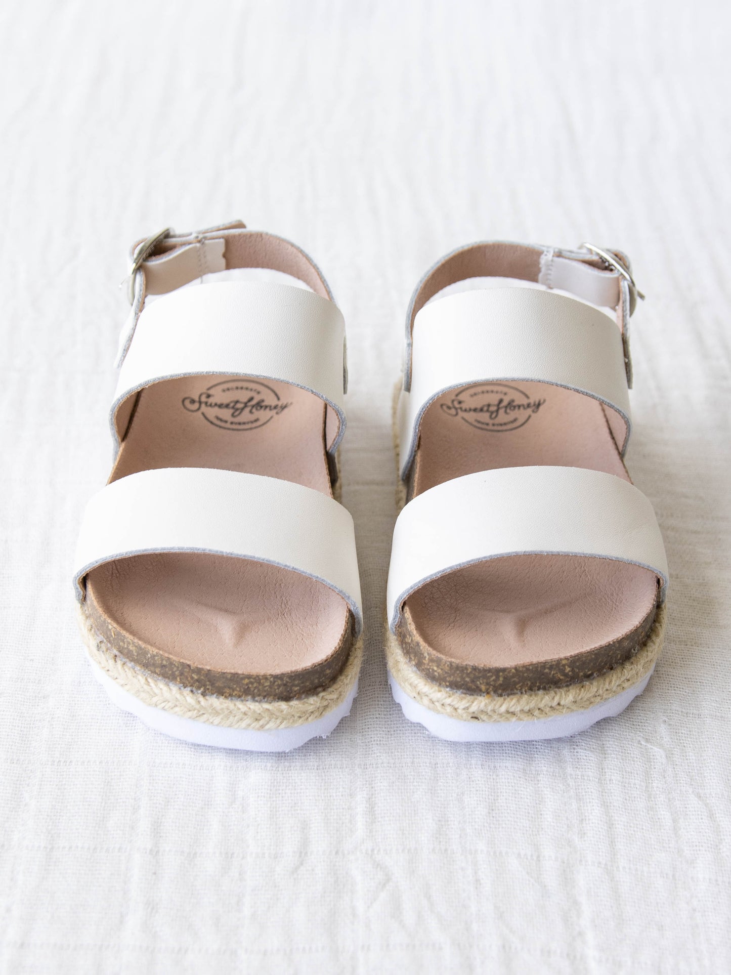 These Strappy Cork Sandals are made of wide strips of Ivory manmade leather, cork sole, and have a metal adjustable buckle.