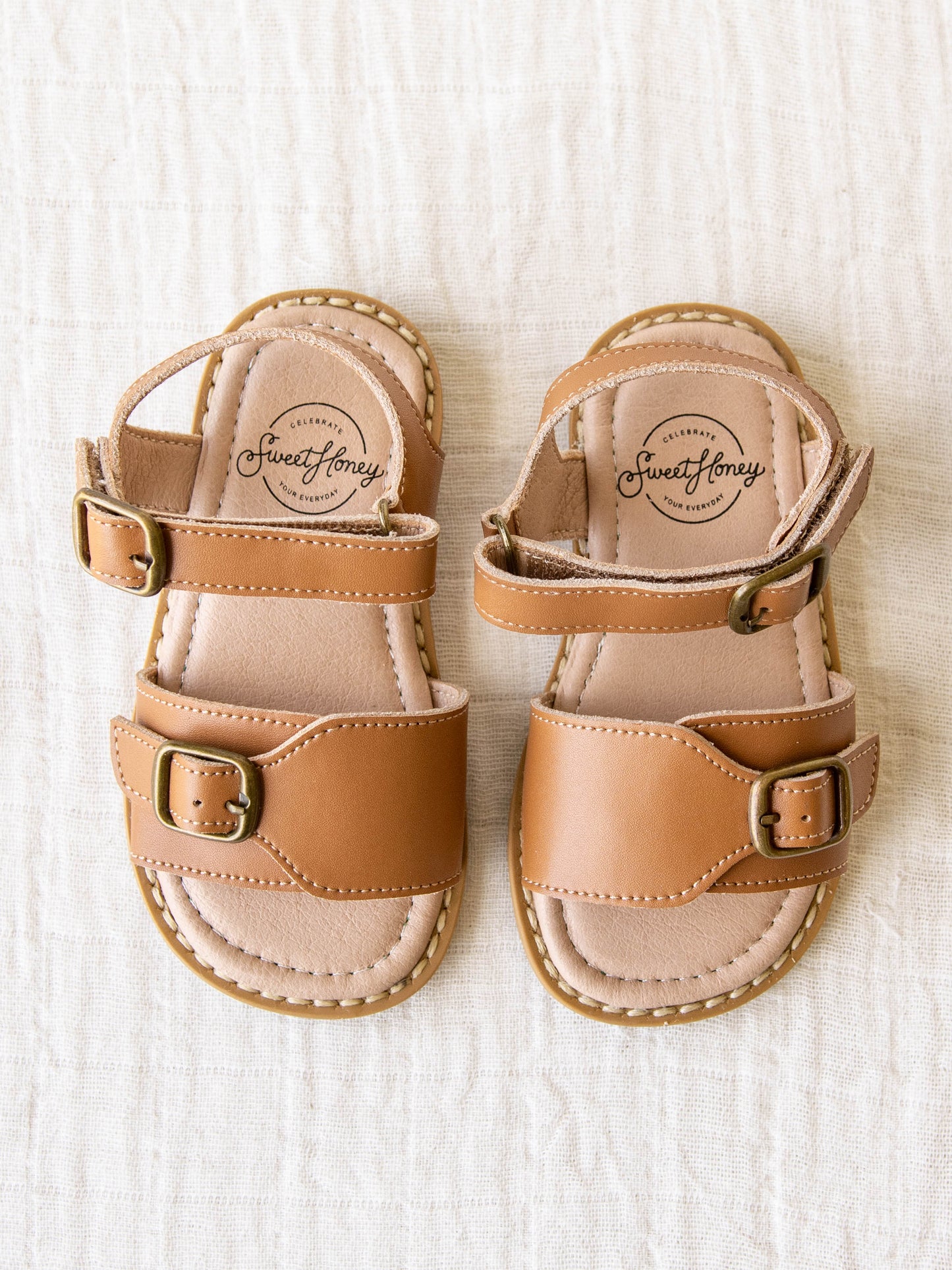 This pair of brown colored manmade leather rubber soled sandals with two adjustable metal buckles are the perfect finish to an outfit. 