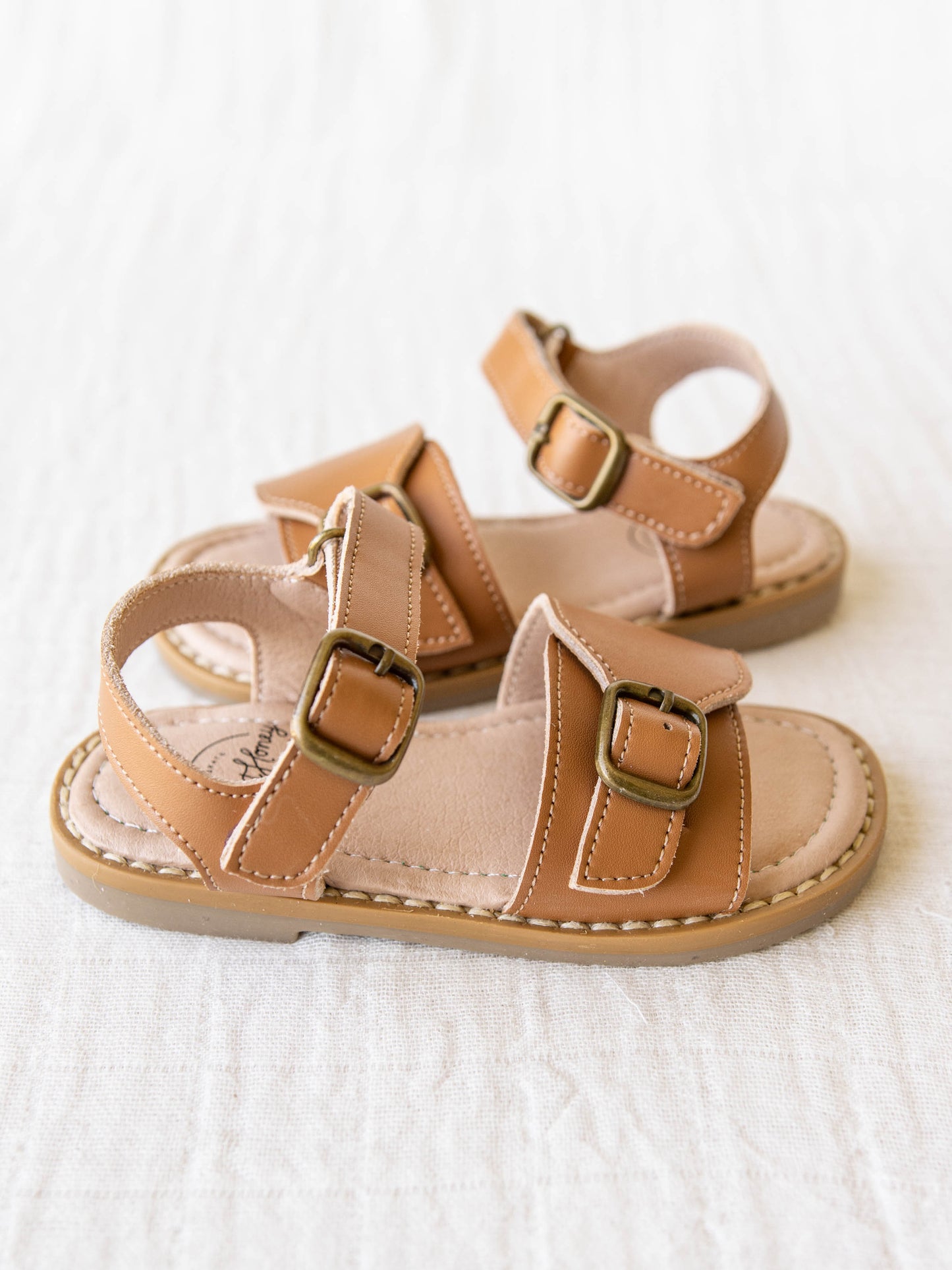 This pair of brown colored manmade leather rubber soled sandals with two adjustable metal buckles are the perfect finish to an outfit. 